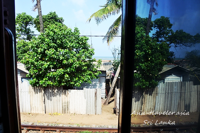 スリランカの列車窓から見えるヤシの木と民家と海岸線
