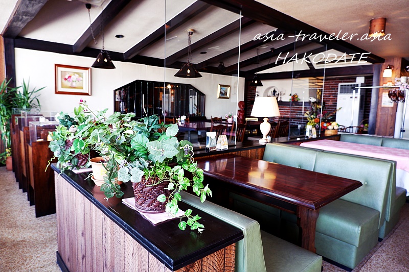 レストランヨシヤの緑のボックス席と観葉植物が並ぶ落ち着いた店内