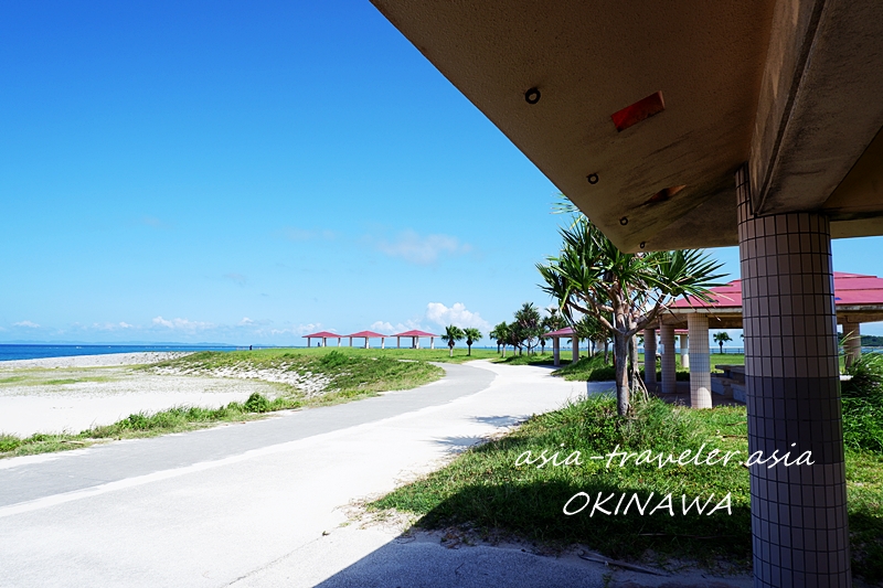 豊崎・美らサンビーチ沿いに並ぶ赤い屋根の東屋と青い海