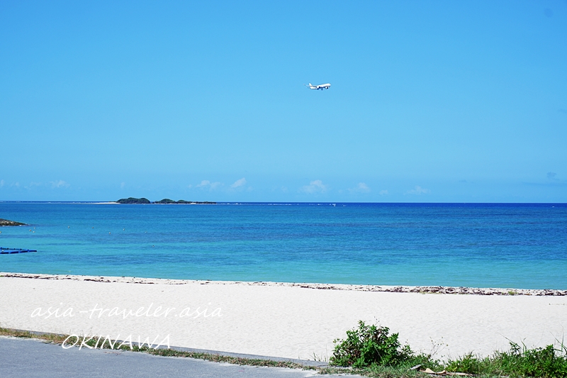 美らサンビーチ上空を飛ぶ飛行機と青い海