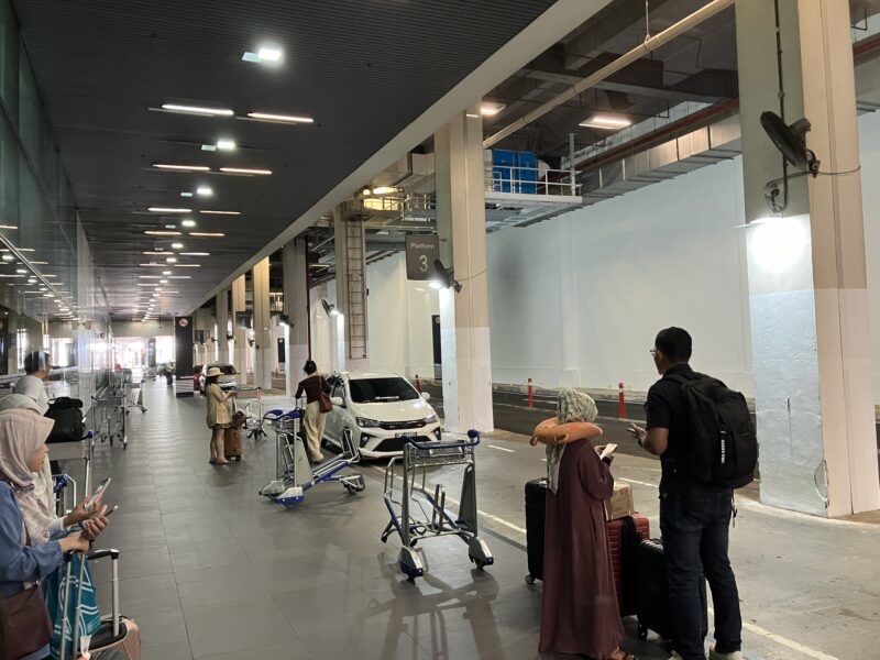 クアラルンプール空港到着ロビーのプラットフォーム3で荷物を持つ旅行者たち