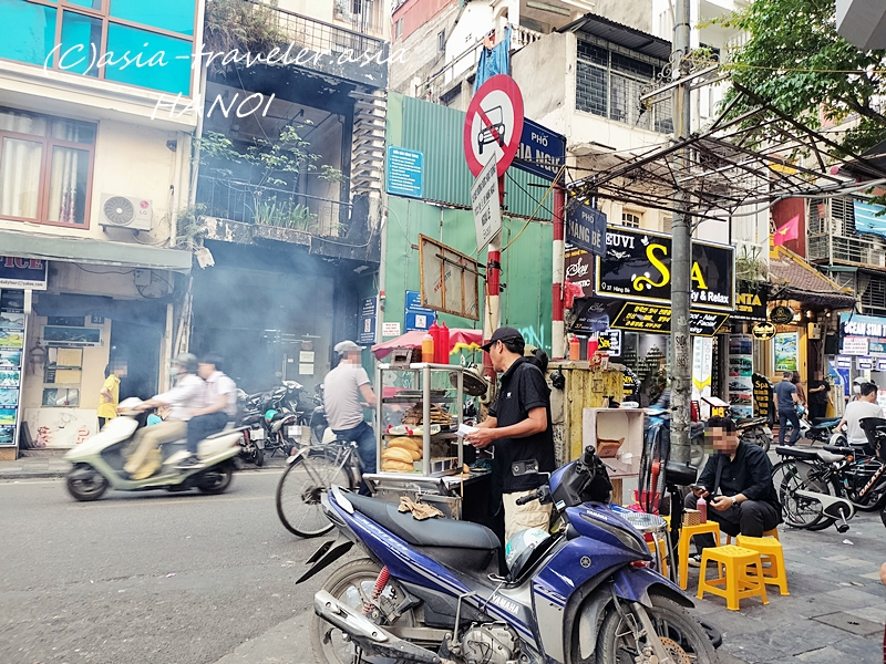 ハノイ旧市街ハンベー通りの煙立ち込める屋台とバイクが行き交う路地