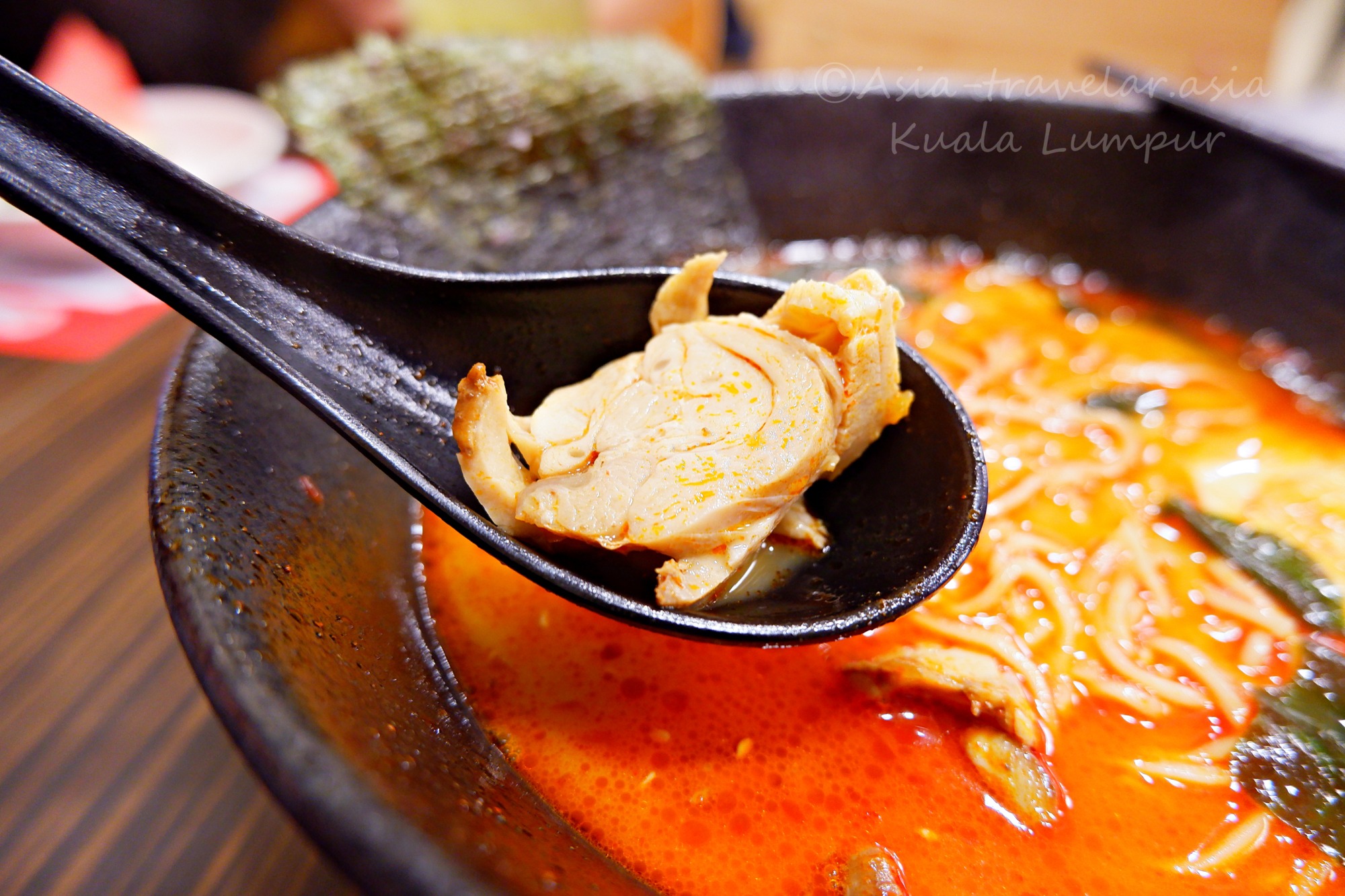 クアラルンプール1番ラーメンの赤辛スープとチキンチャーシューをレンゲですくったアップ