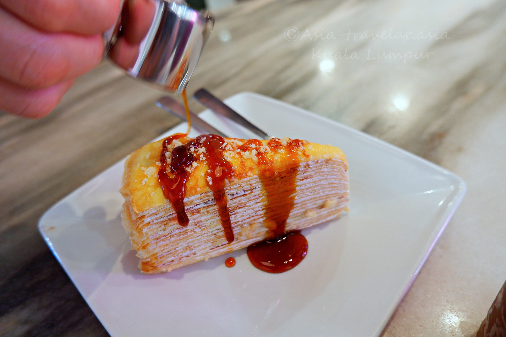 クアラルンプール空港カフェのグラ・マラッカ入りミルクレープにシロップをかける瞬間