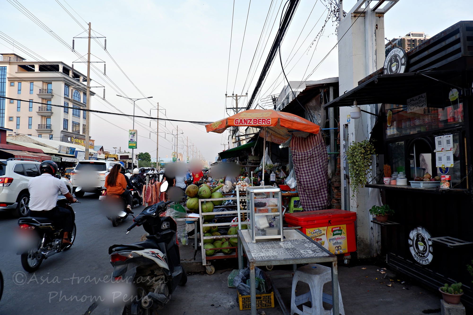 プノンペンの路上に並ぶヤシの実売り屋台と行き交うバイク
