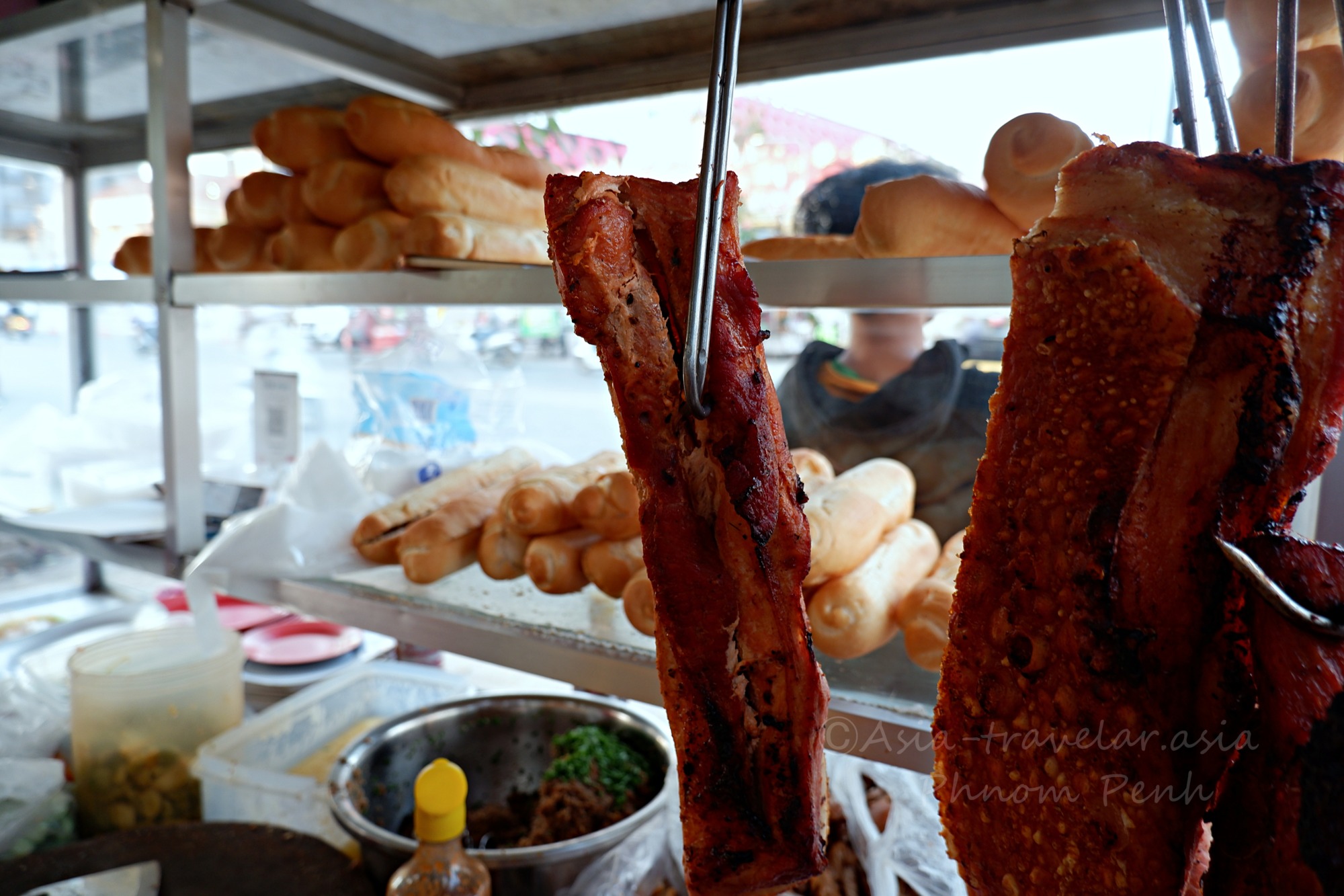 プノンペンのヌンパン屋台に吊るされた焼き三枚肉とバゲット