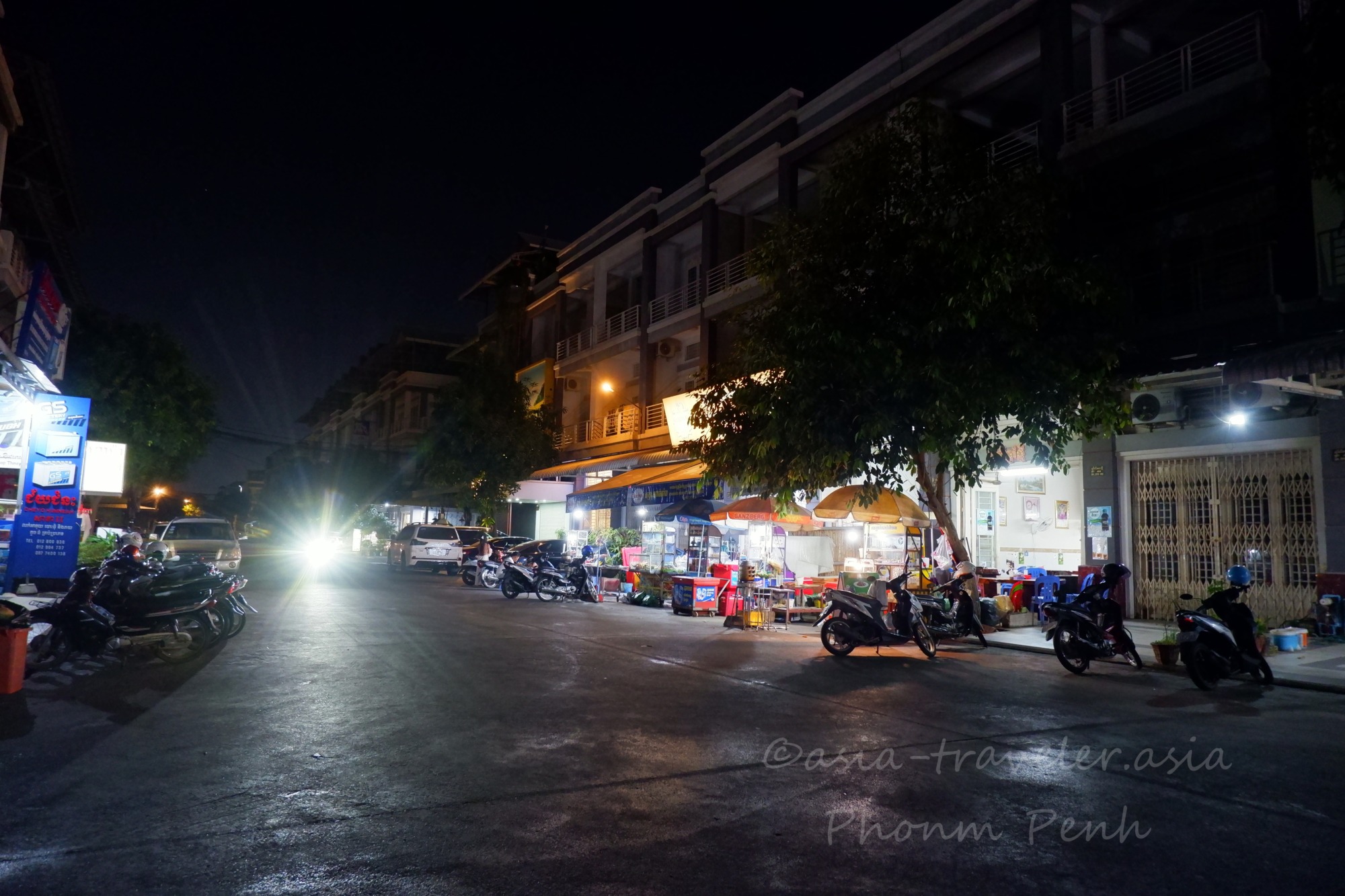 プノンペンの夜の路地に並ぶ屋台と停まるバイク