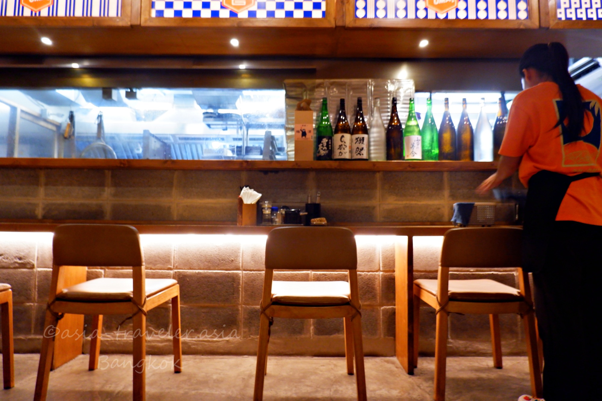 バンコク・博多うま馬のカウンター席と日本酒瓶が並ぶ店内