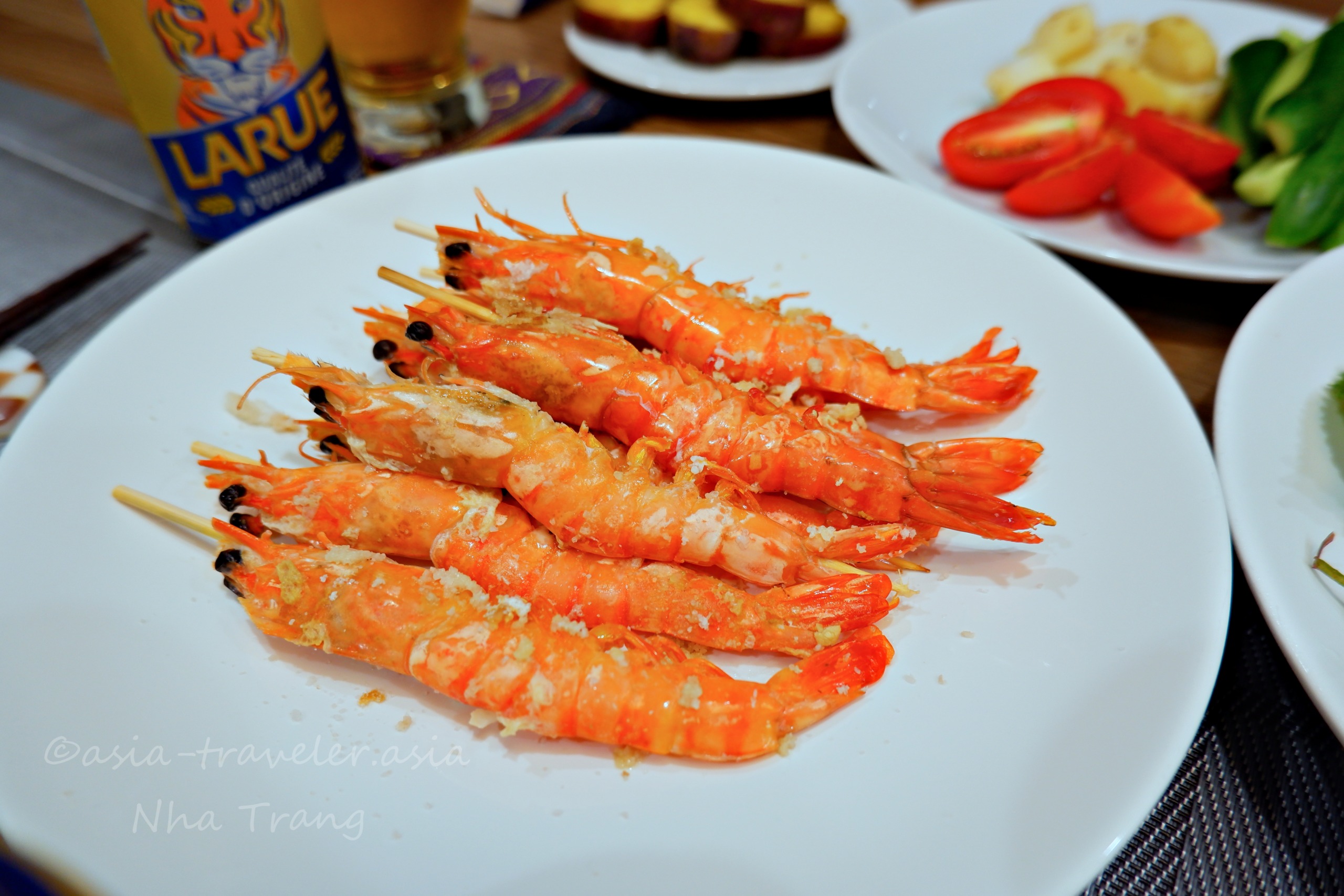 ニャチャンの活き海老を串焼きにした皿とLARUEビール
