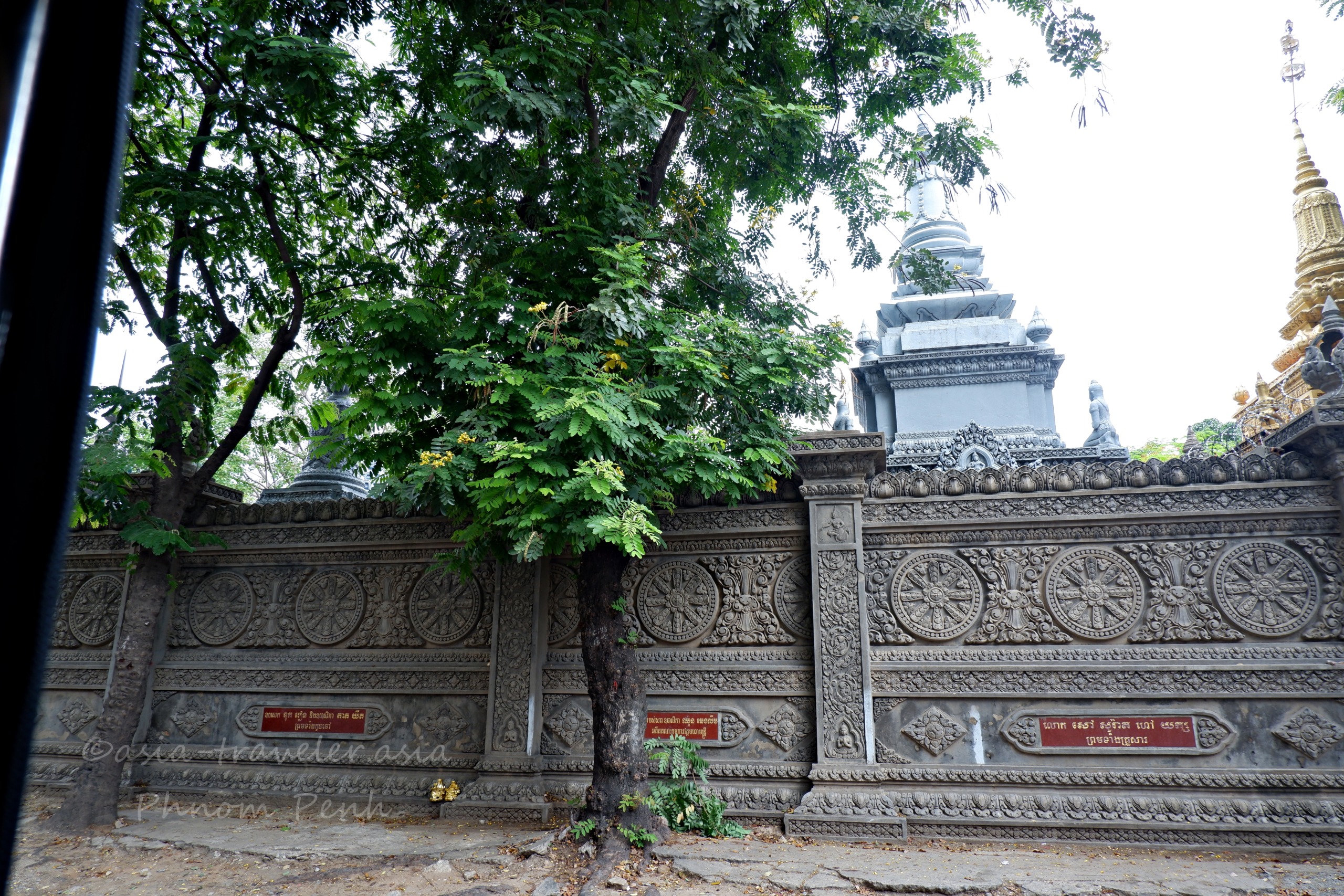 プノンペンの寺院外壁に刻まれた精緻な彫刻と白いストゥーパ