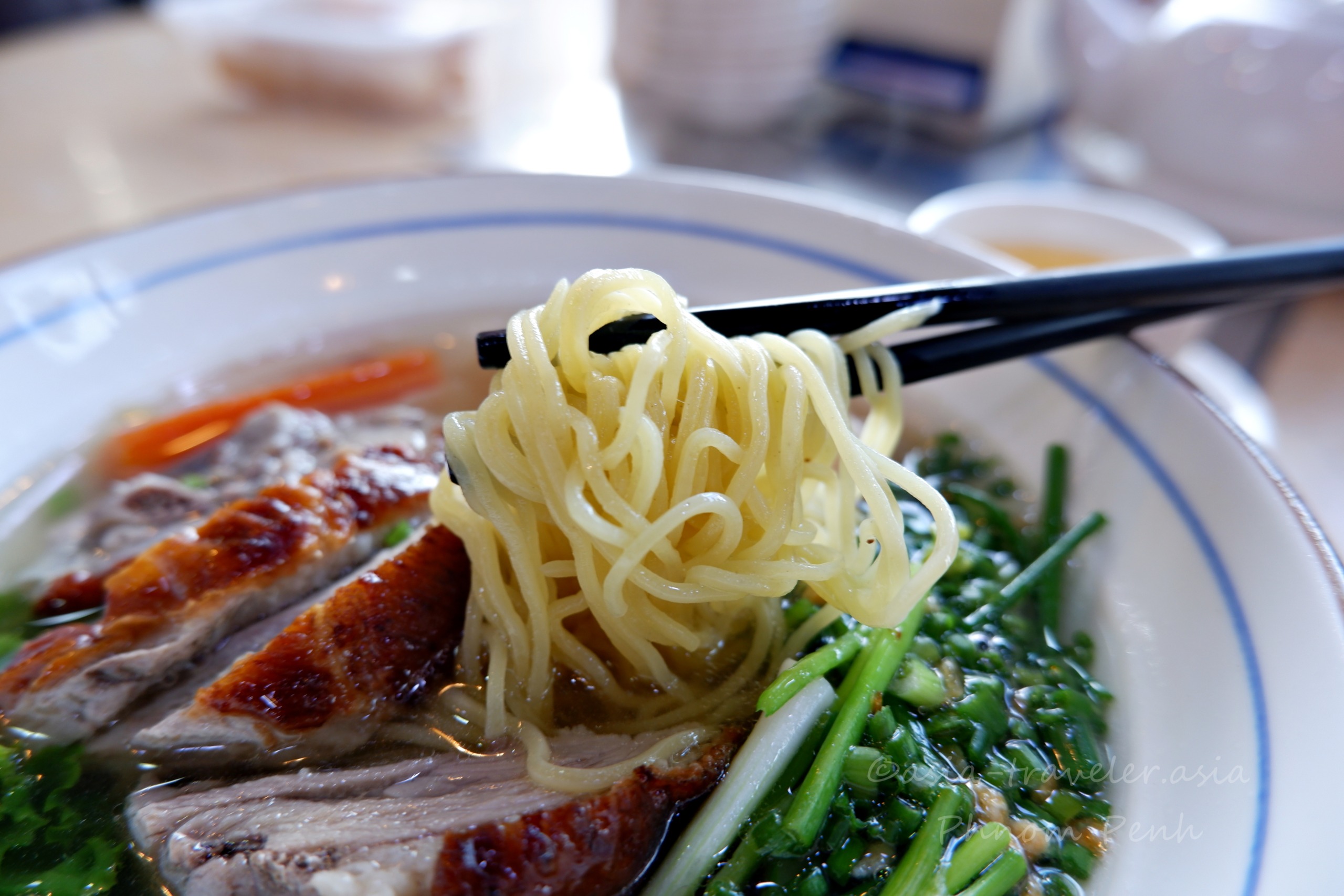 箸で持ち上げた焼きアヒル入りワンタン麺のアップ