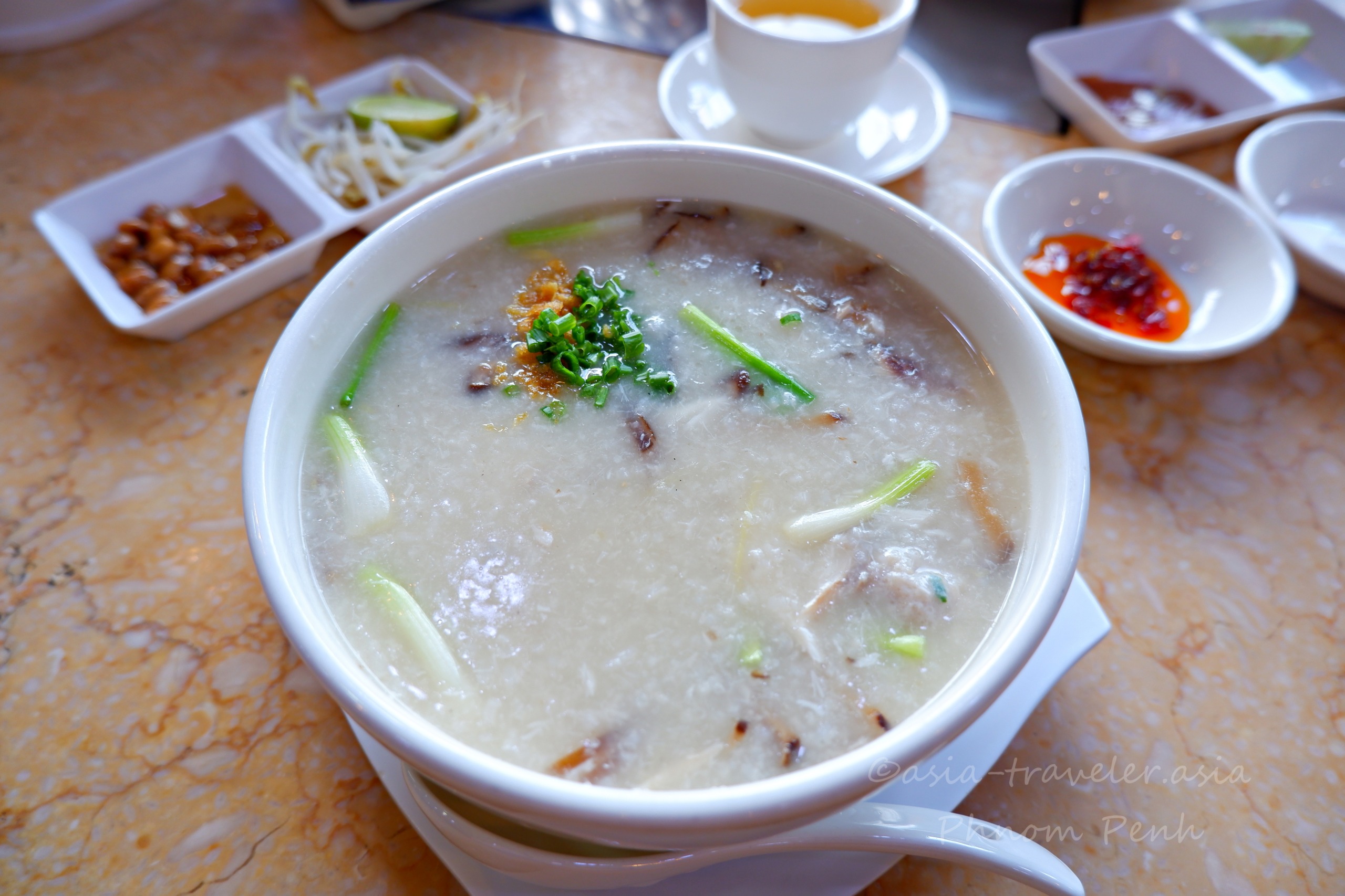 プノンペンの茶餐廳で供される魚片粥と小皿トッピング