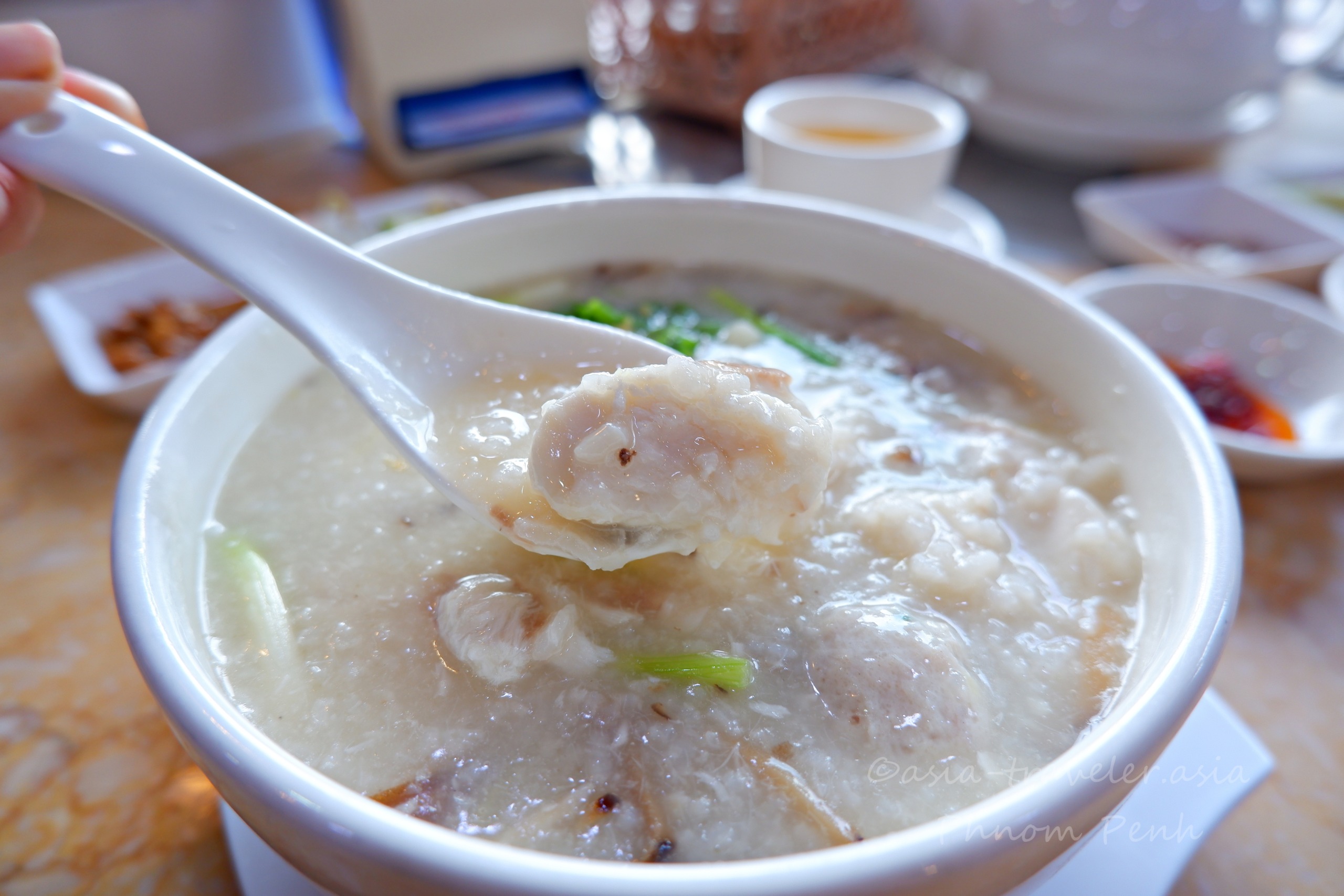 プノンペンの魚片粥をレンゲですくうアップ