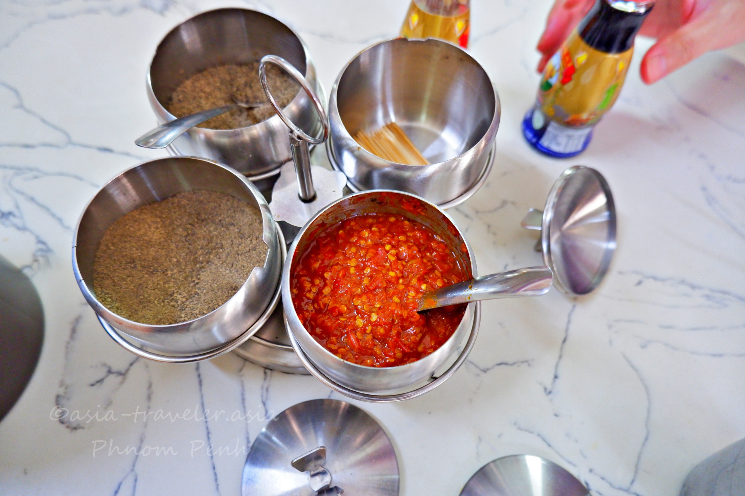 プノンペンのヌンパン店に並ぶチリソースや胡椒などの卓上調味料セット