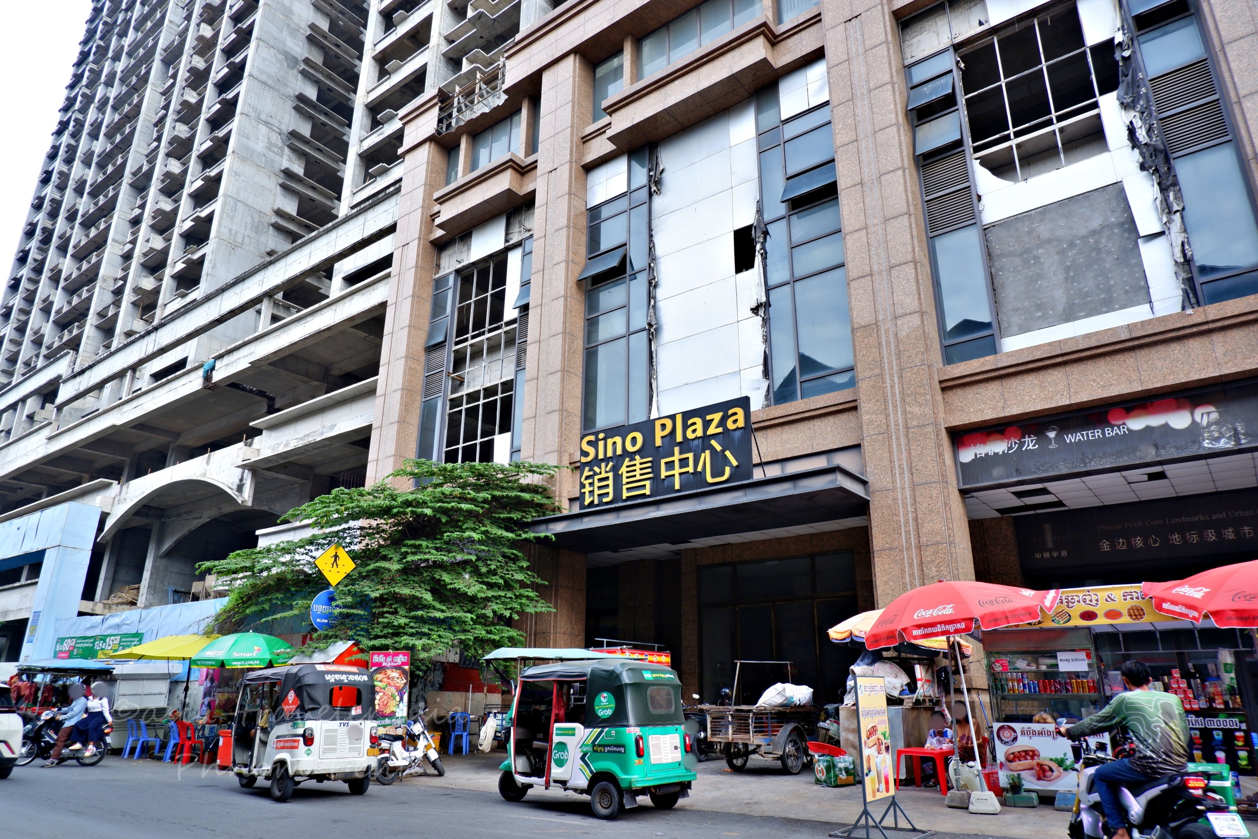 プノンペン中心部のSino Plaza外観とトゥクトゥクが並ぶ中国語看板の街並み