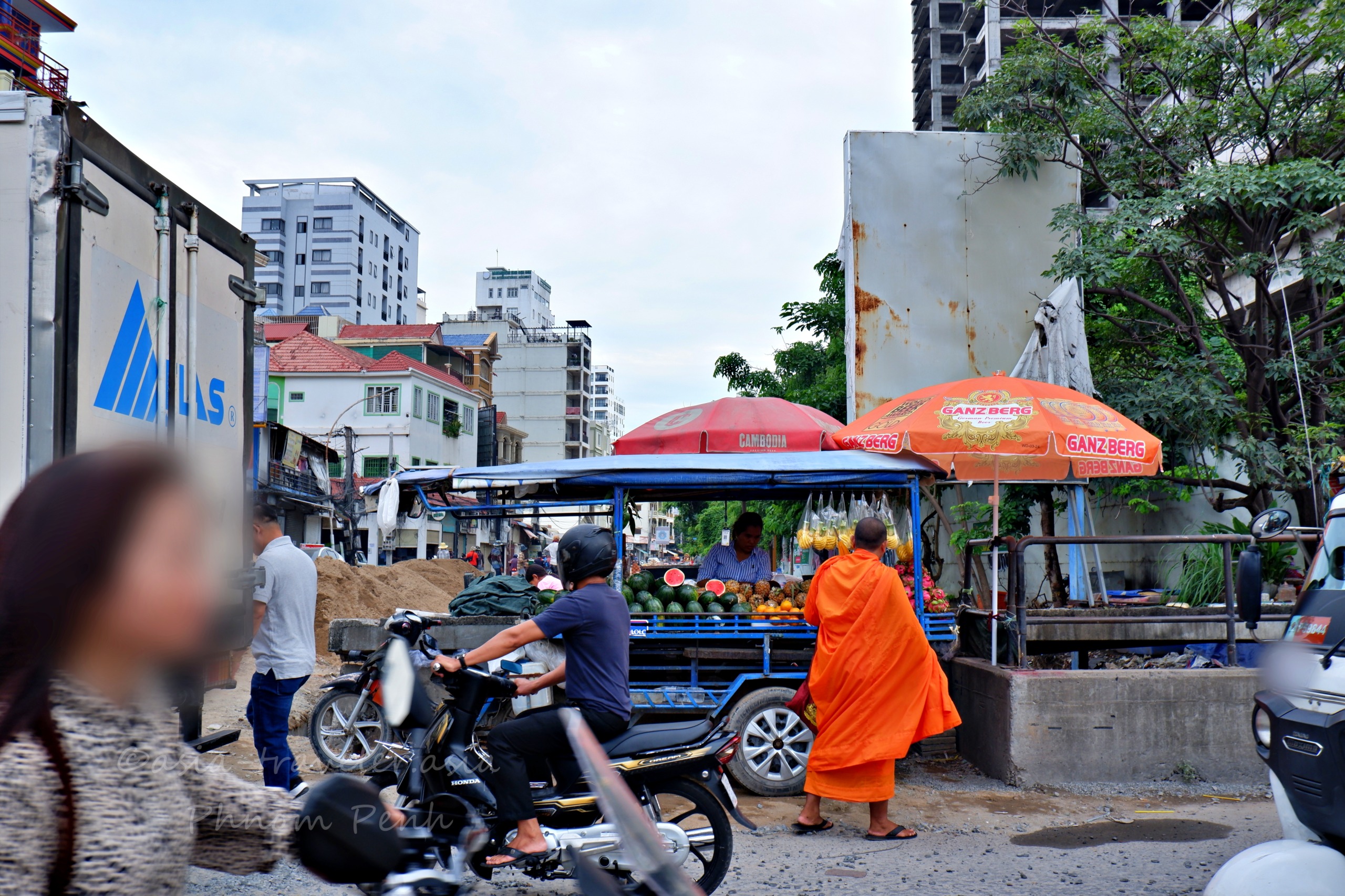 プノンペンの街角で托鉢僧とバイクが行き交うローカルな風景