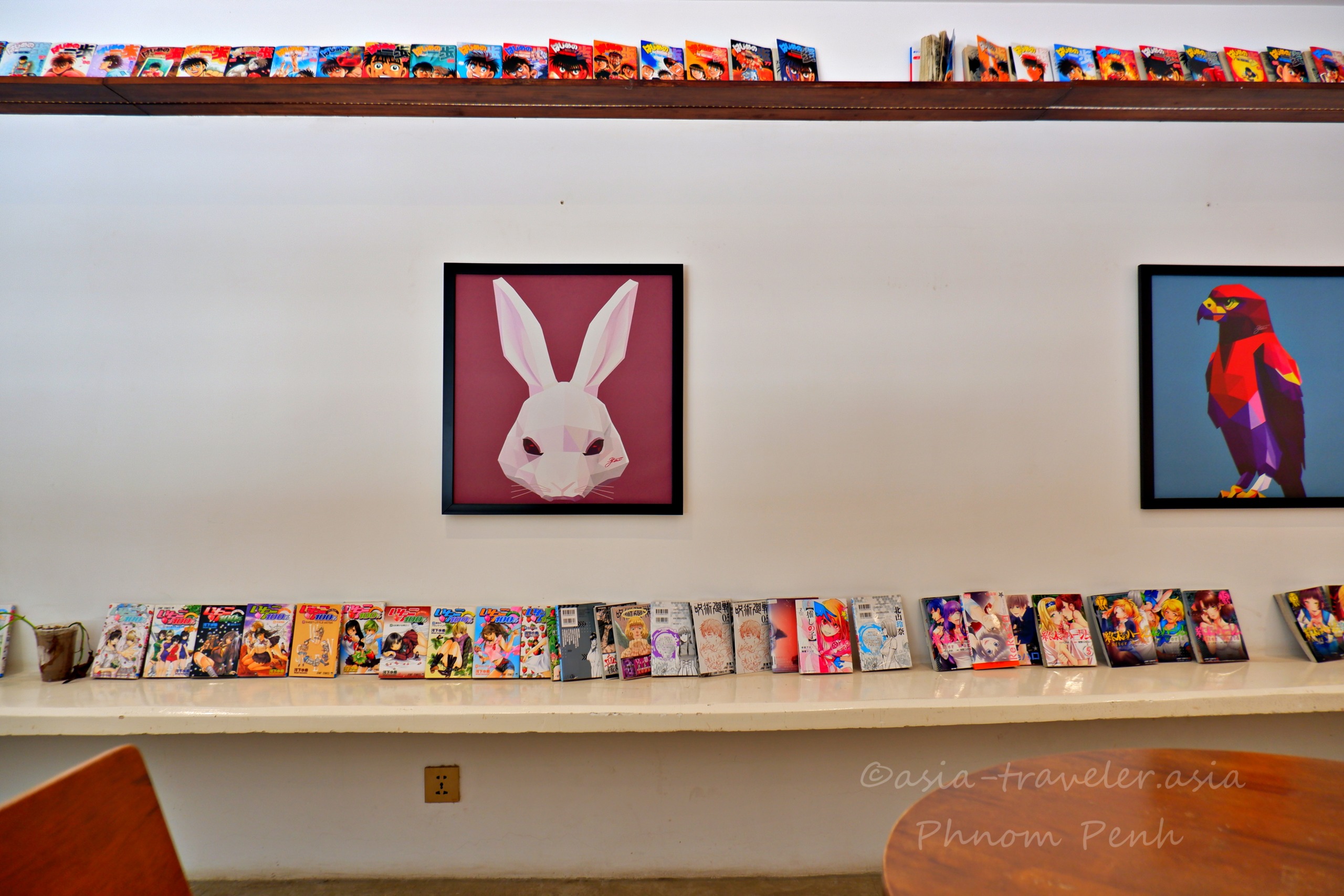 プノンペンの秋葉原カフェ店内に並ぶ日本の漫画本とアートパネル