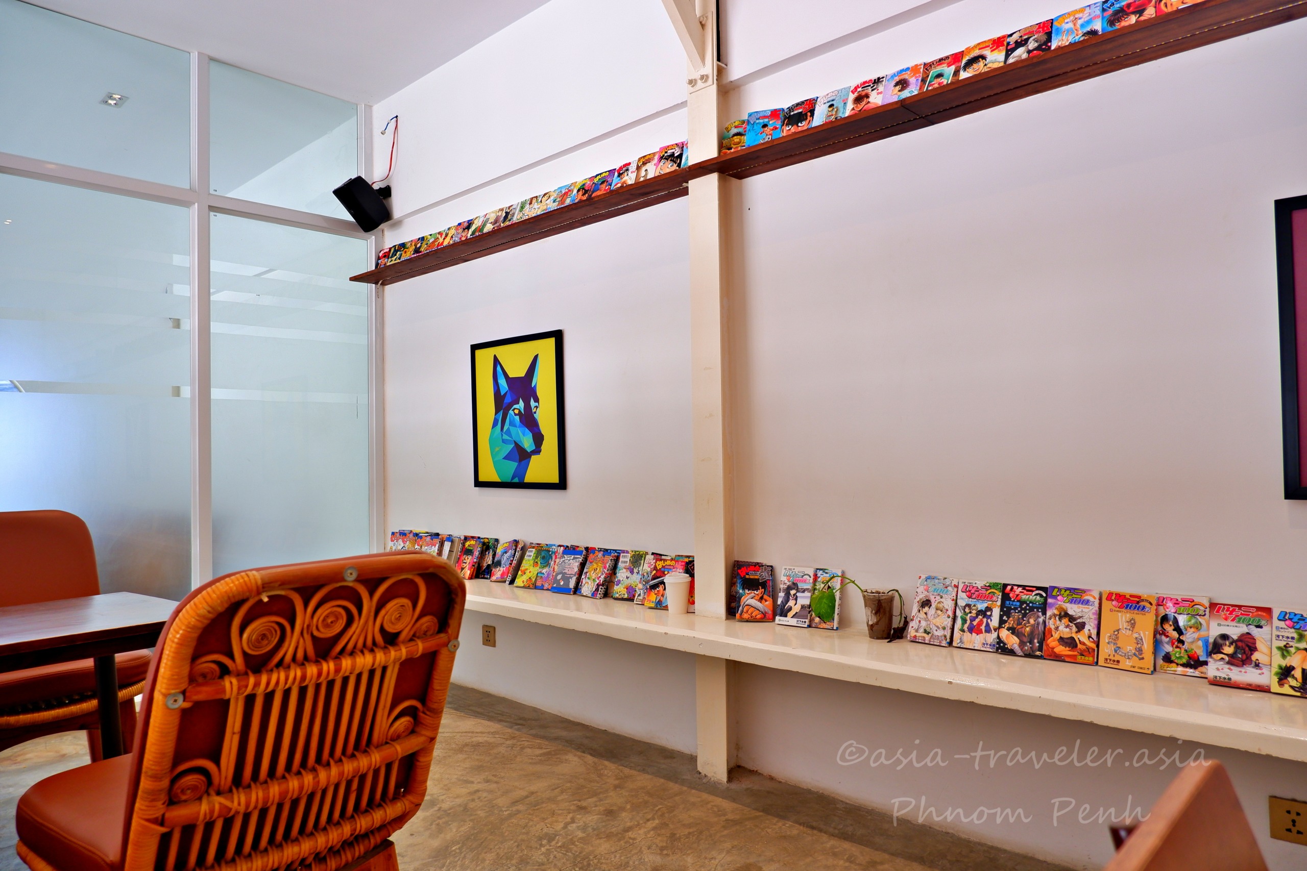 プノンペンの秋葉原カフェ店内に並ぶ日本の漫画本とカラフルな犬のアート
