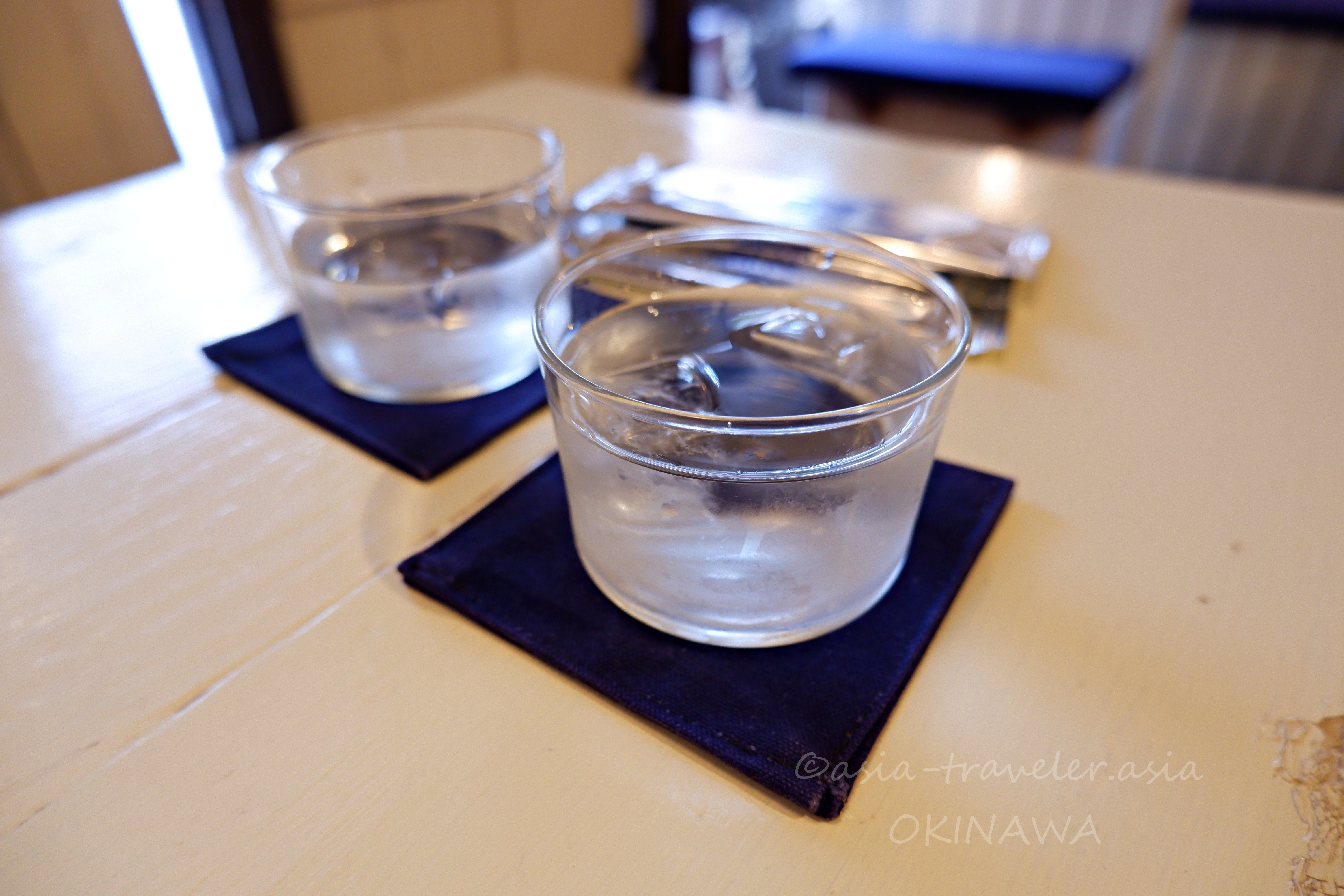 那覇カフネのテーブルに置かれた紺コースターと冷水グラス