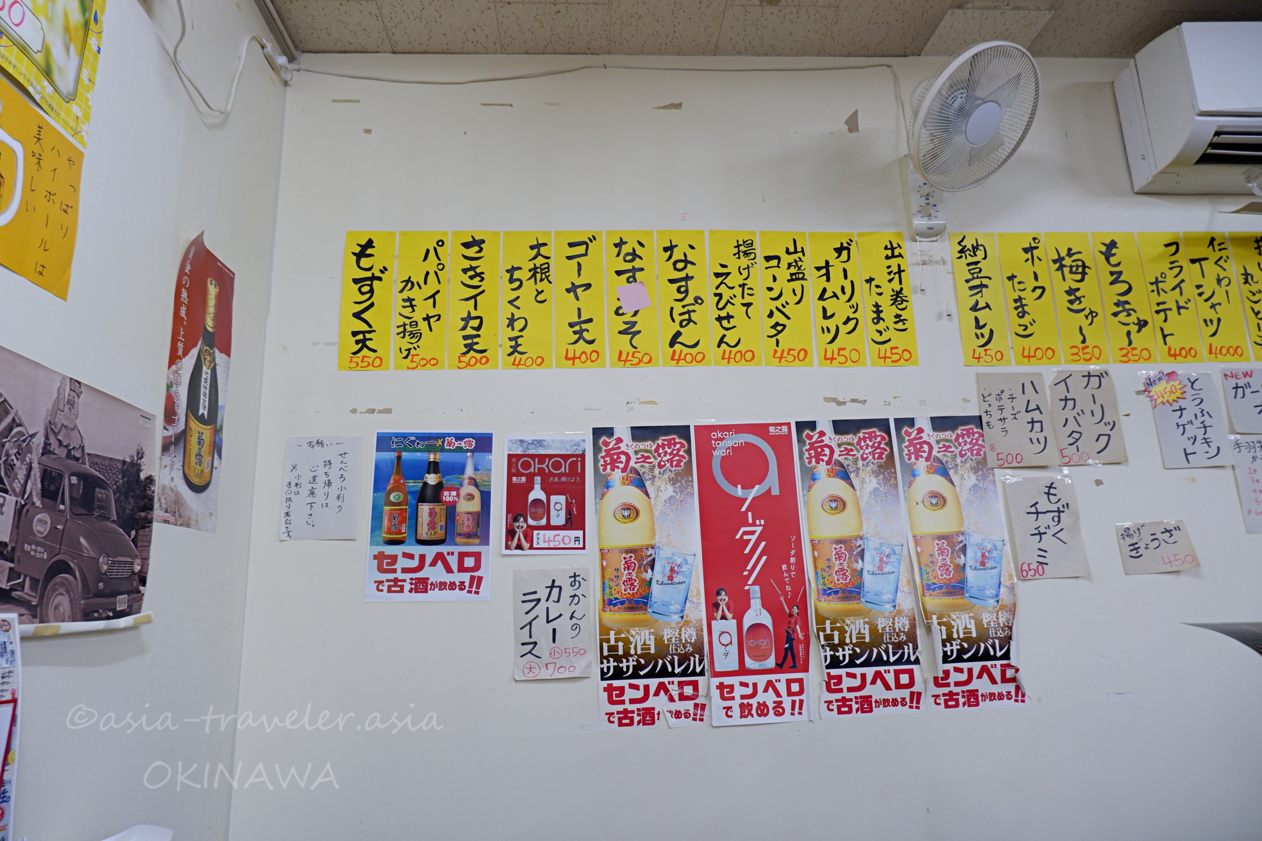 仁ぐゎーの壁一面に貼られた短冊メニューと古酒ポスター