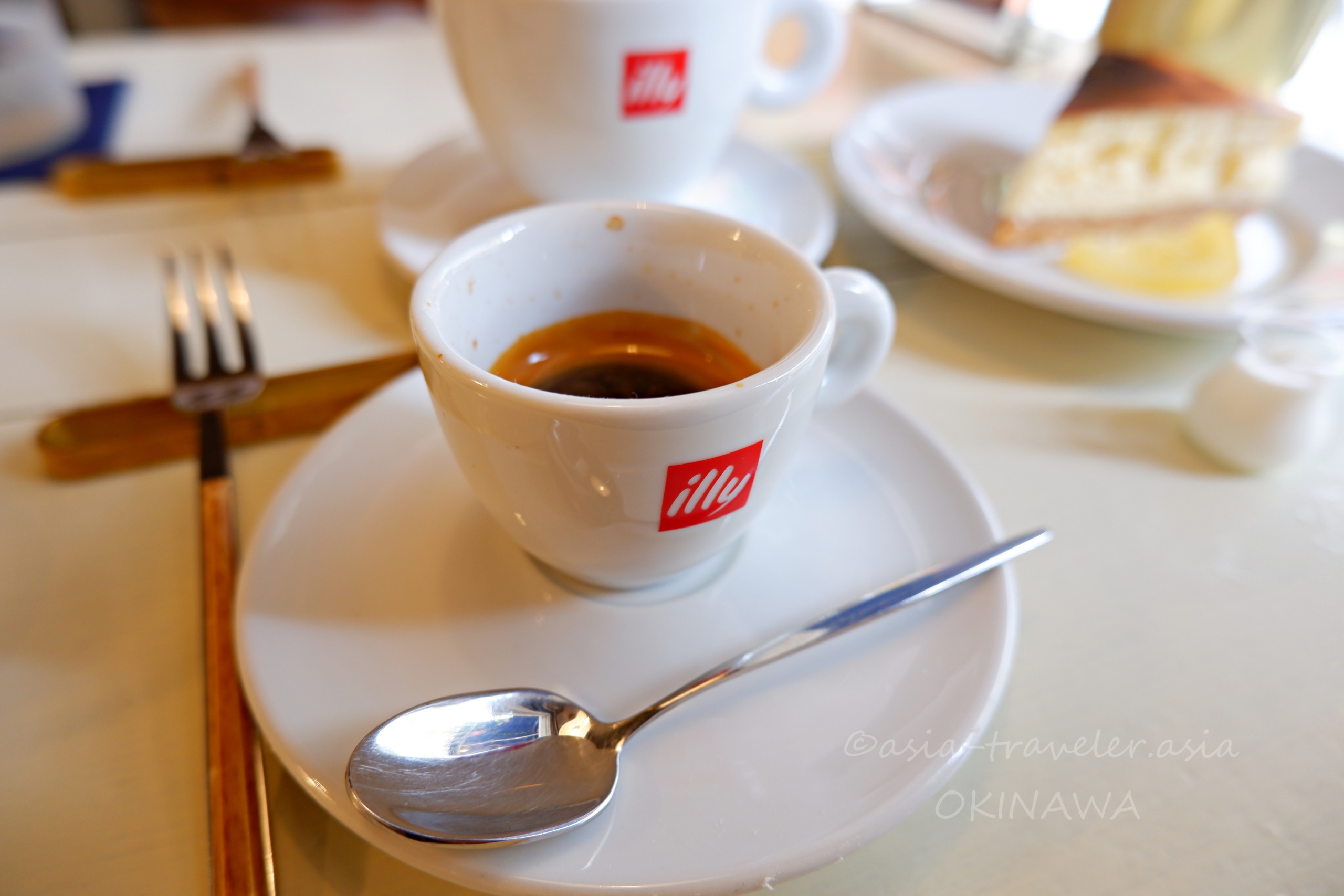 illyカップに注がれたエスプレッソと奥のケーキ