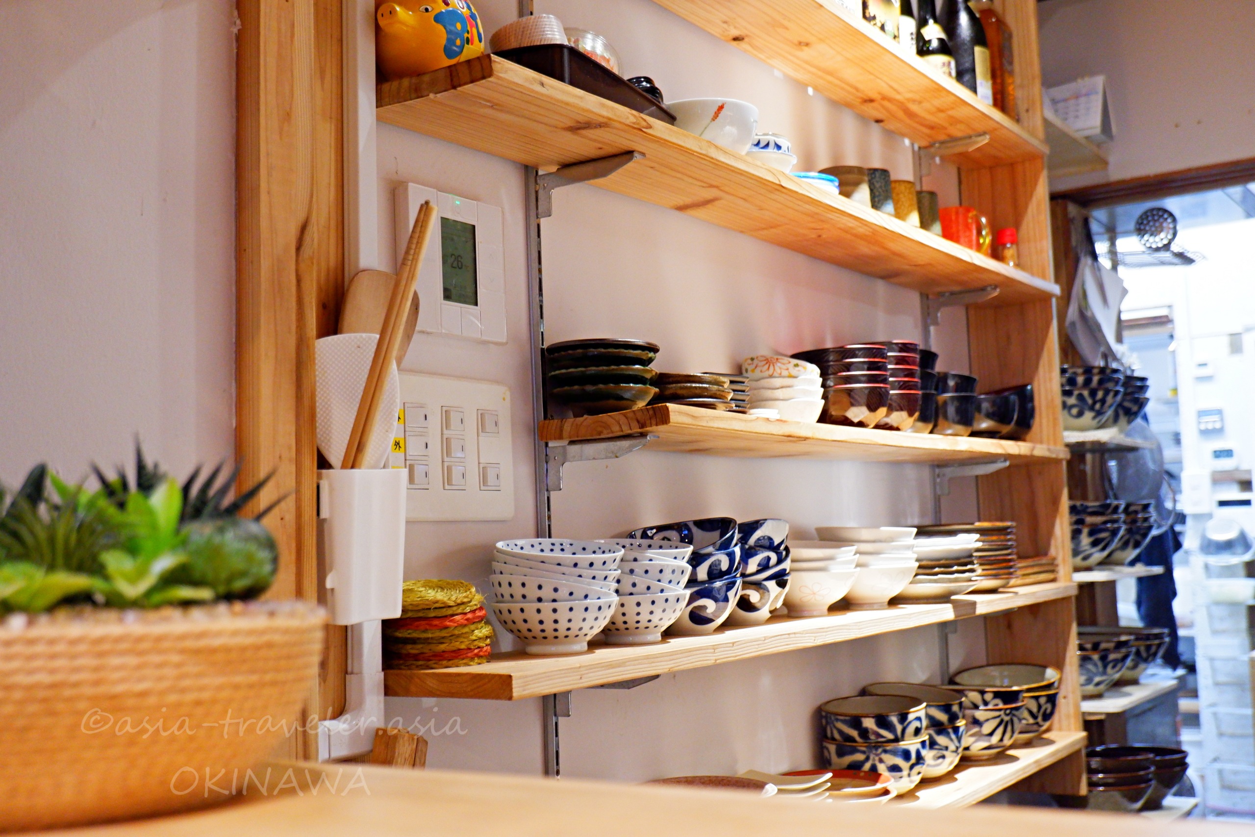 浮島BASEカウンター席から見える沖縄の器が並ぶ木製棚