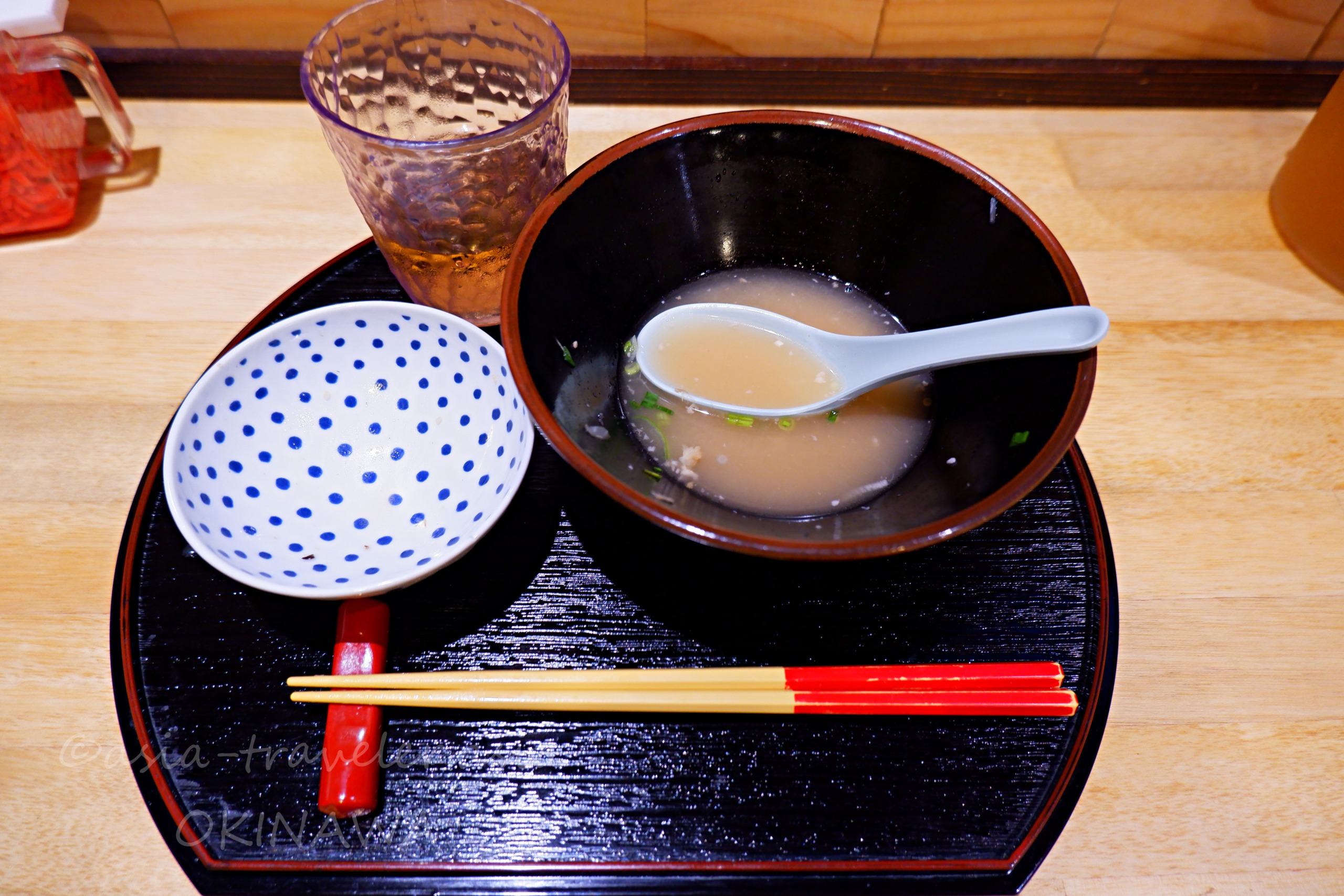 黒塗り盆に並ぶ沖縄そばの出汁スープとドット柄の茶碗