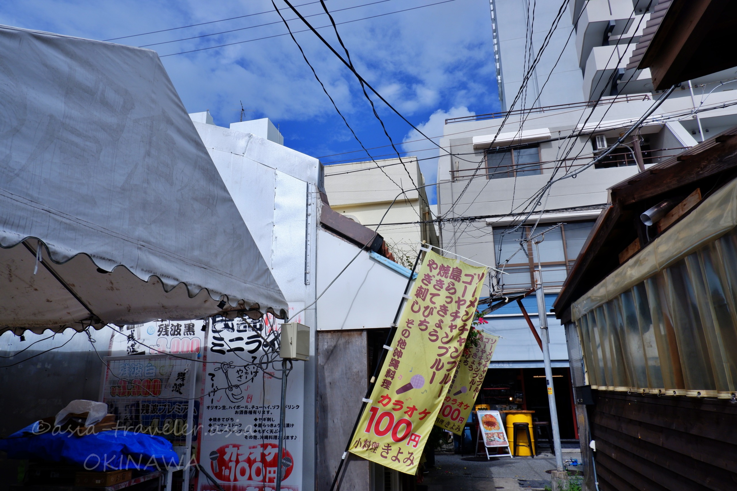 那覇・栄町市場の路地に並ぶ沖縄らしい看板と青空