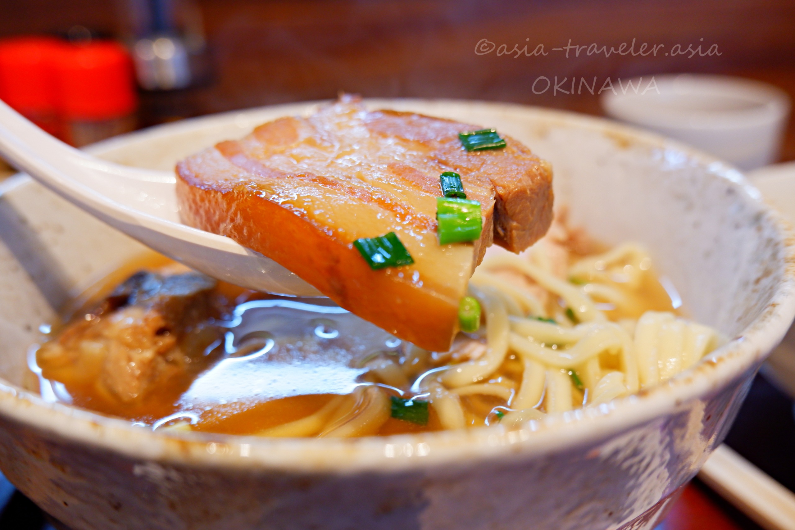 麺屋あんの沖縄そばと箸で持ち上げた三枚肉のアップ