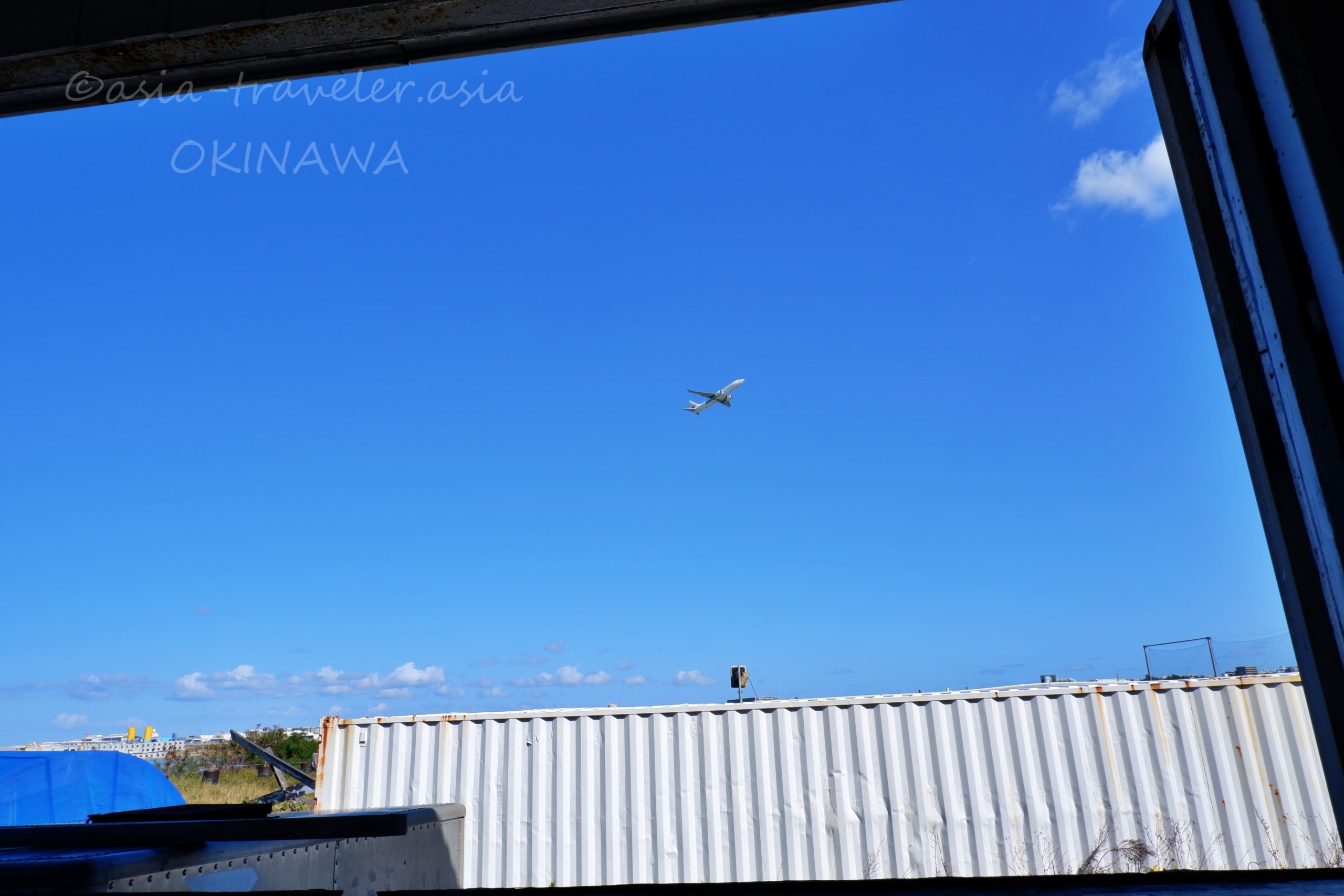 沖縄・瀬長島上空を飛ぶ飛行機と青空