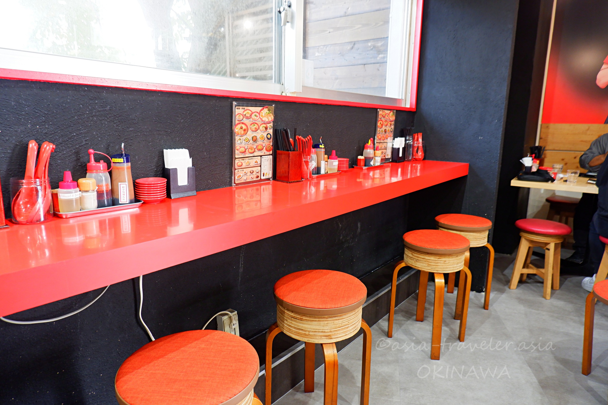 Agu豚久茂地店の赤いカウンター席と丸椅子