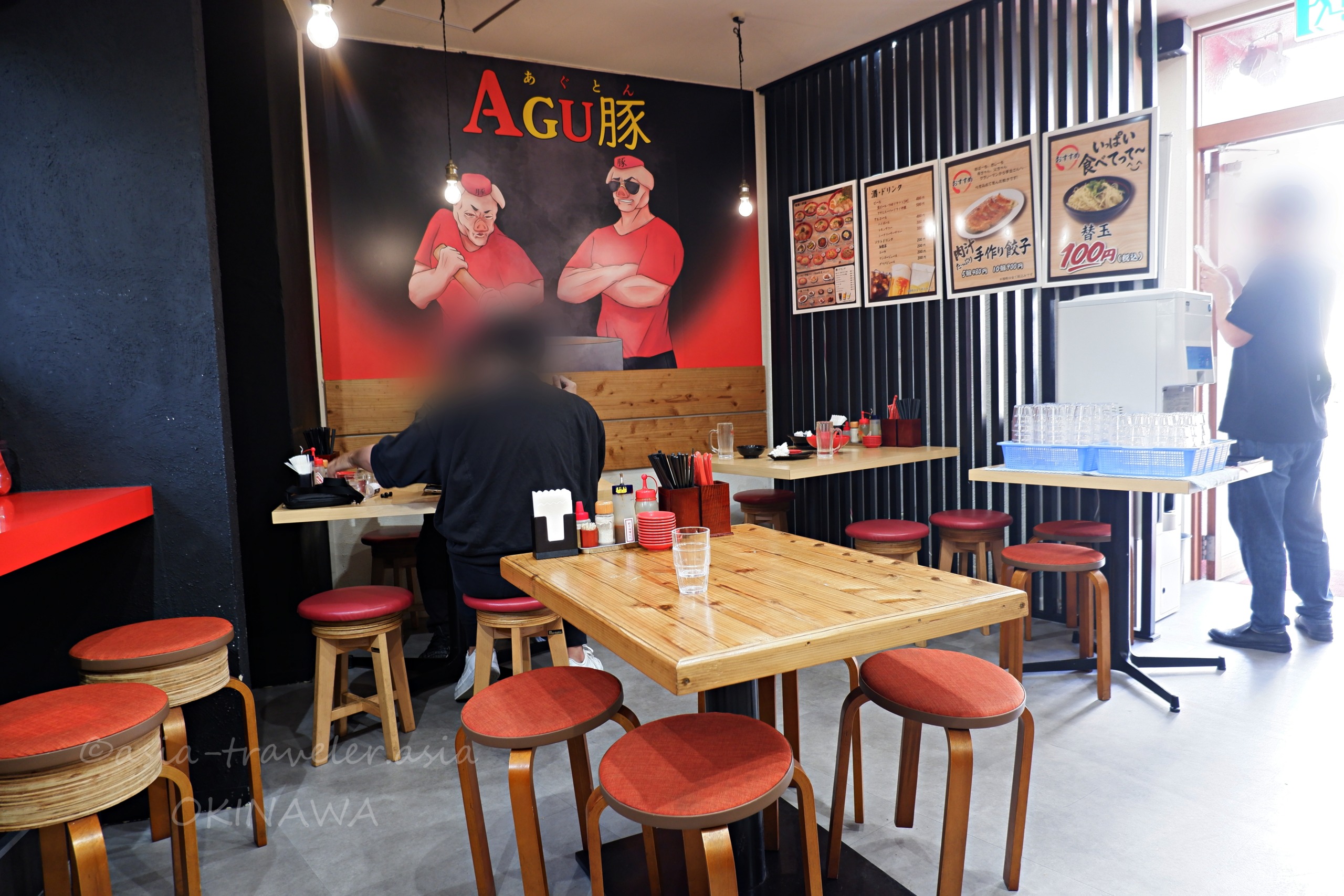 Agu豚久茂地店の赤いスツールが並ぶ店内テーブル席