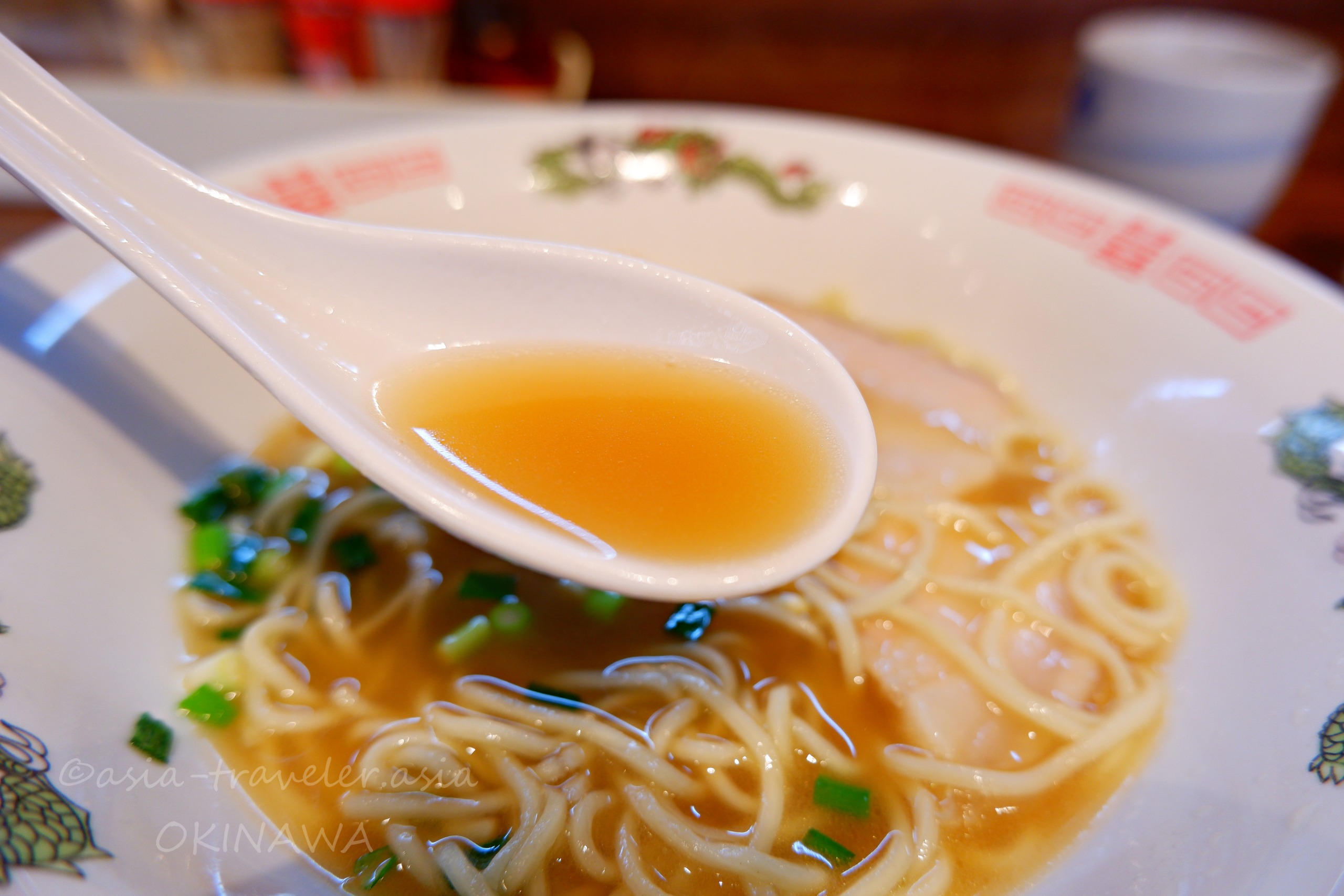 麺屋あんの三枚肉チャーシューラーメンの澄んだスープをレンゲで掬う