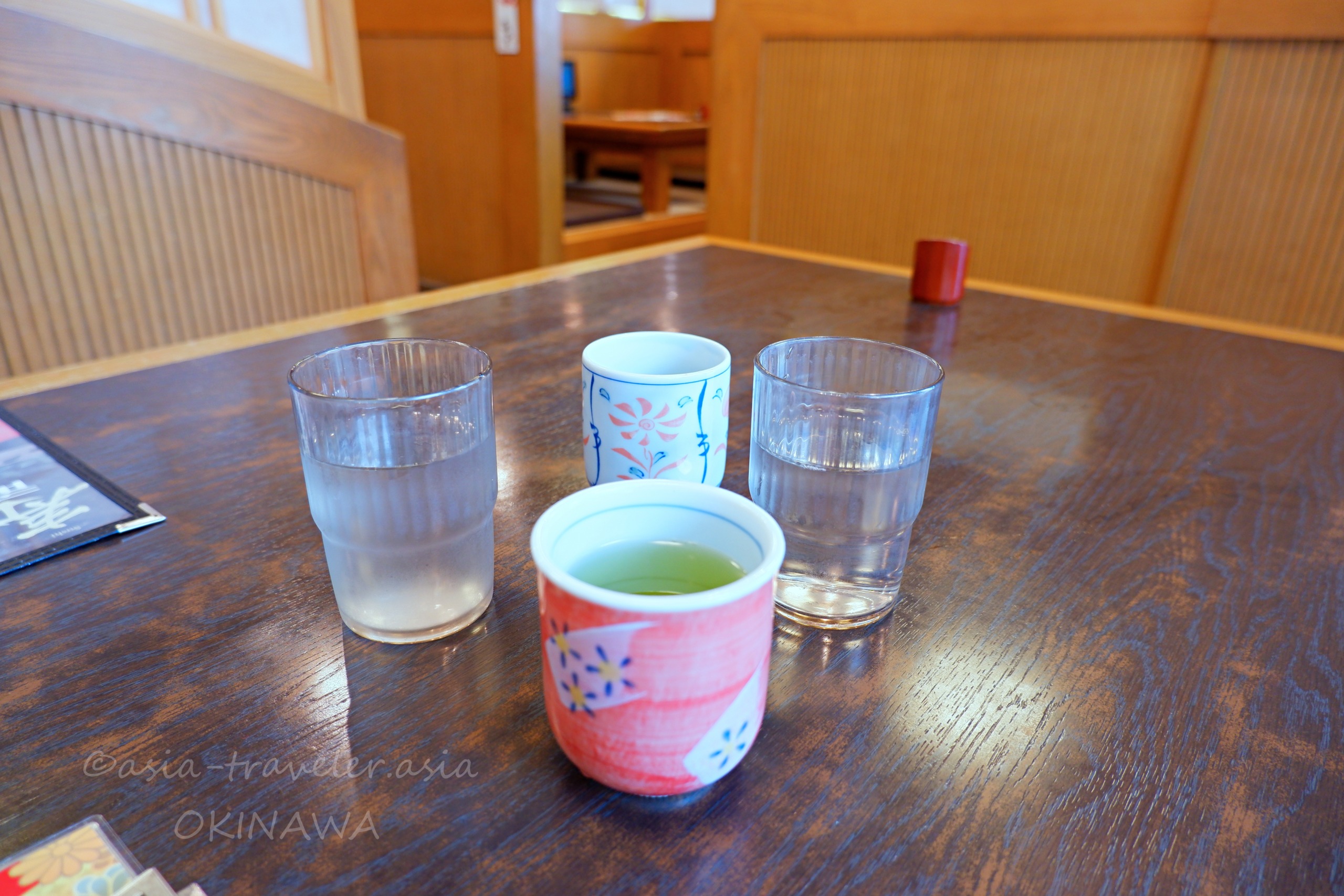 沖縄・和風亭のお冷やと緑茶が並ぶテーブル席