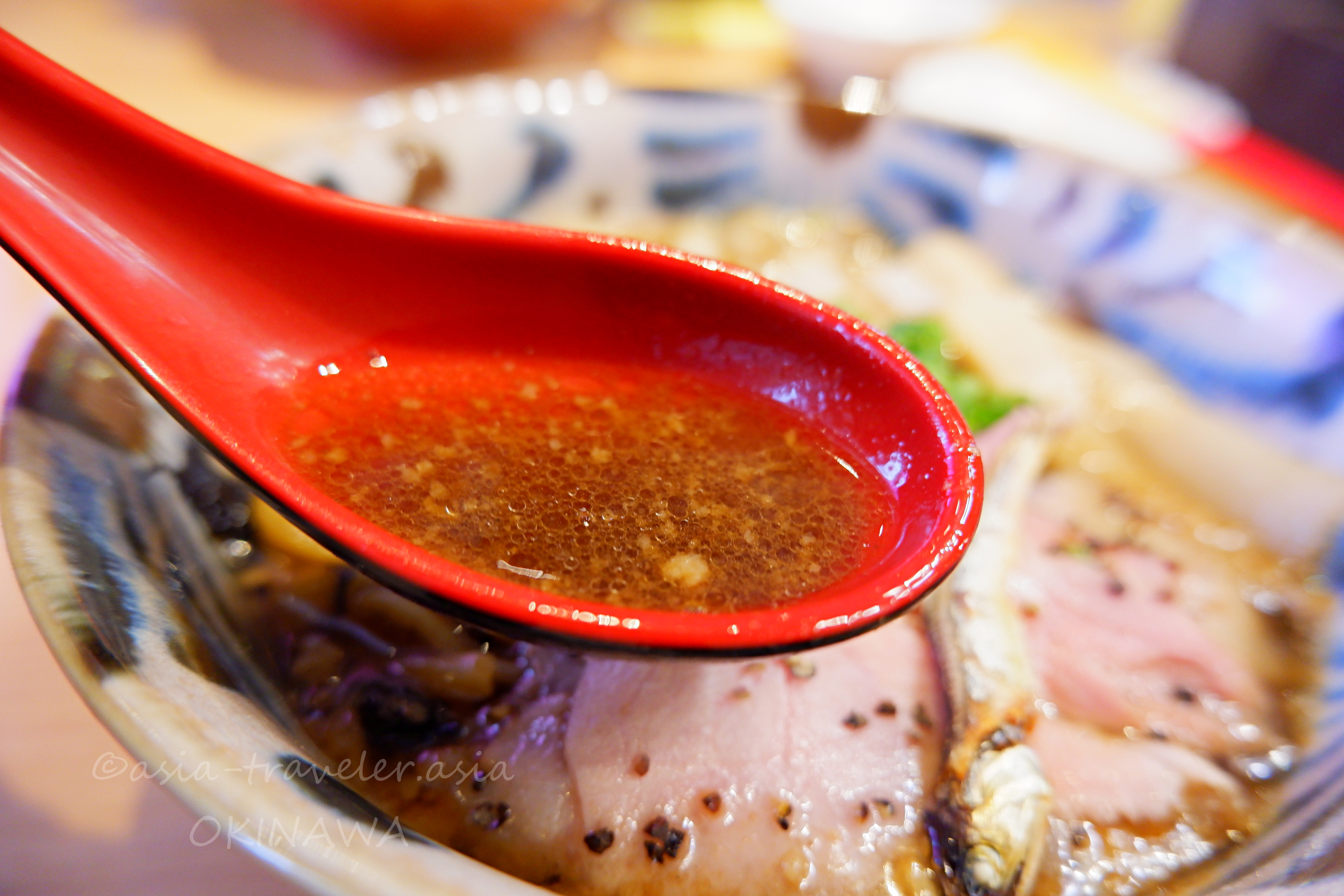 益々の煮干しそばスープを赤いレンゲですくうアップ