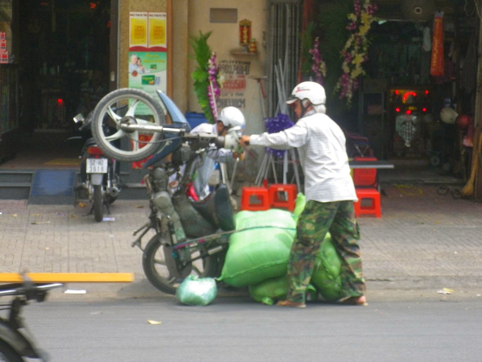 ホーチミン・チョロン街頭でバイクに荷物を積みすぎた男性