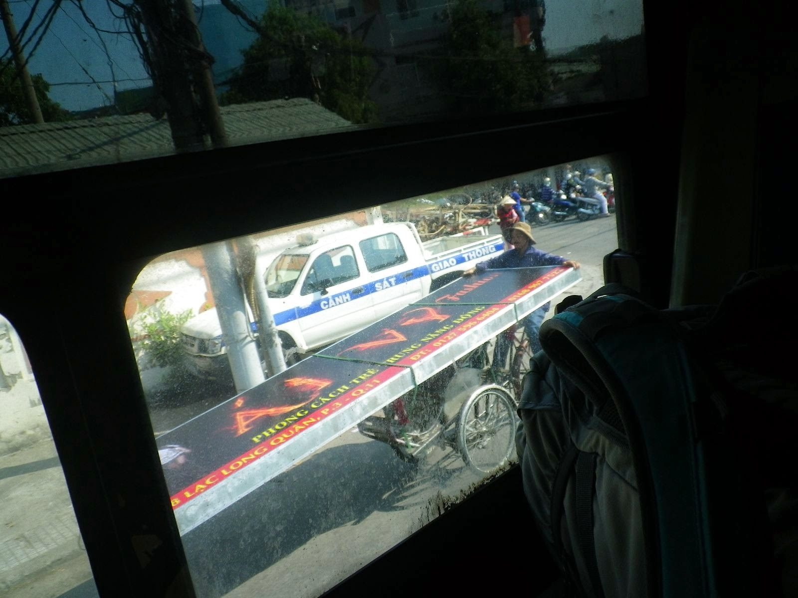 バスの車窓越しに見えるベトナム警察車両と三輪車