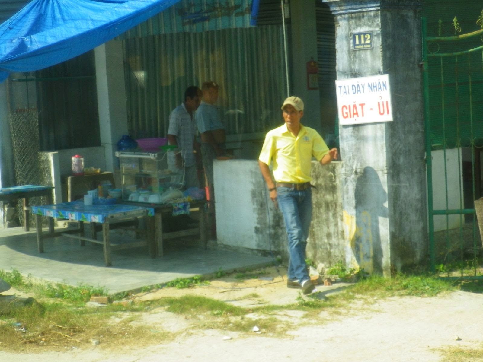 ベトナムの路上でGIẶT-ỦIの看板前に立つ男性