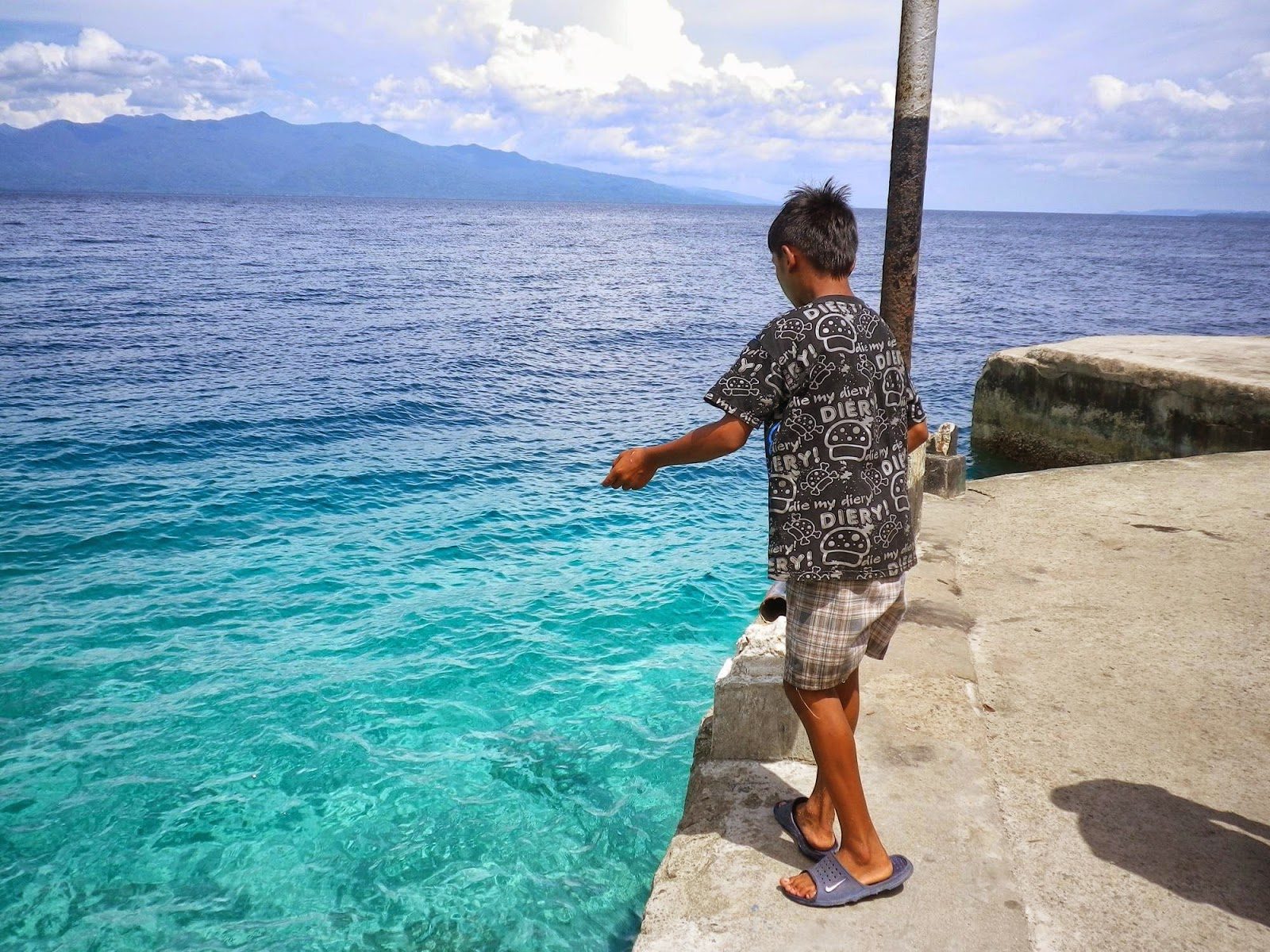 アンボンの港で糸と針だけで魚を釣る地元の少年