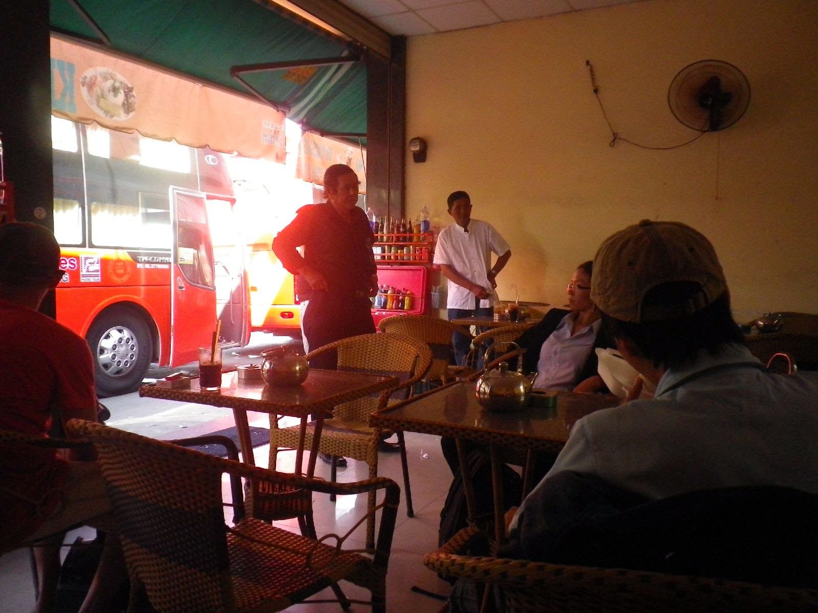 バスターミナル隣の食堂でバインミーを待つ旅行者と僧侶