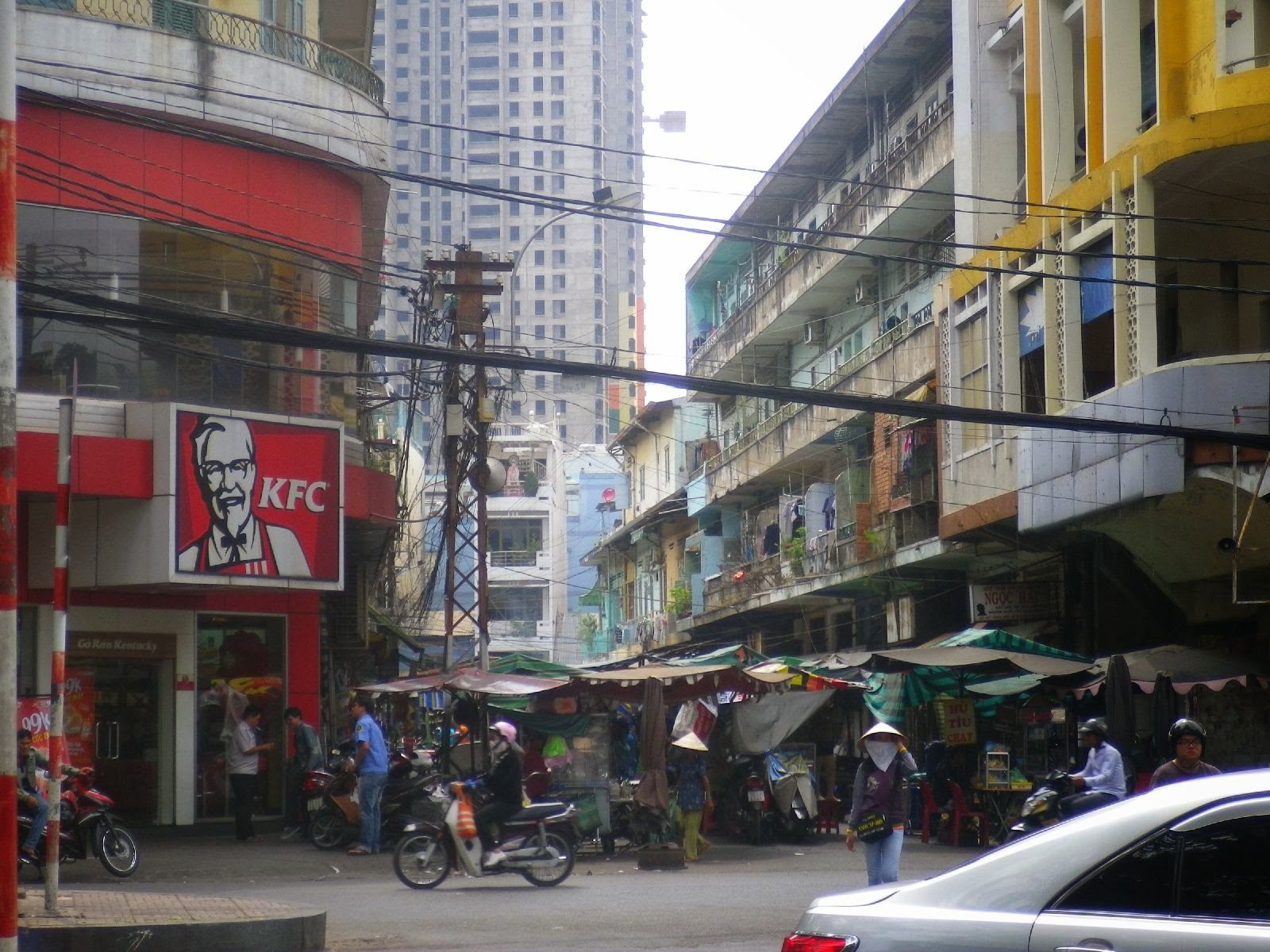 ホーチミン市チョロン地区のKFC前を走るバイクと露店街