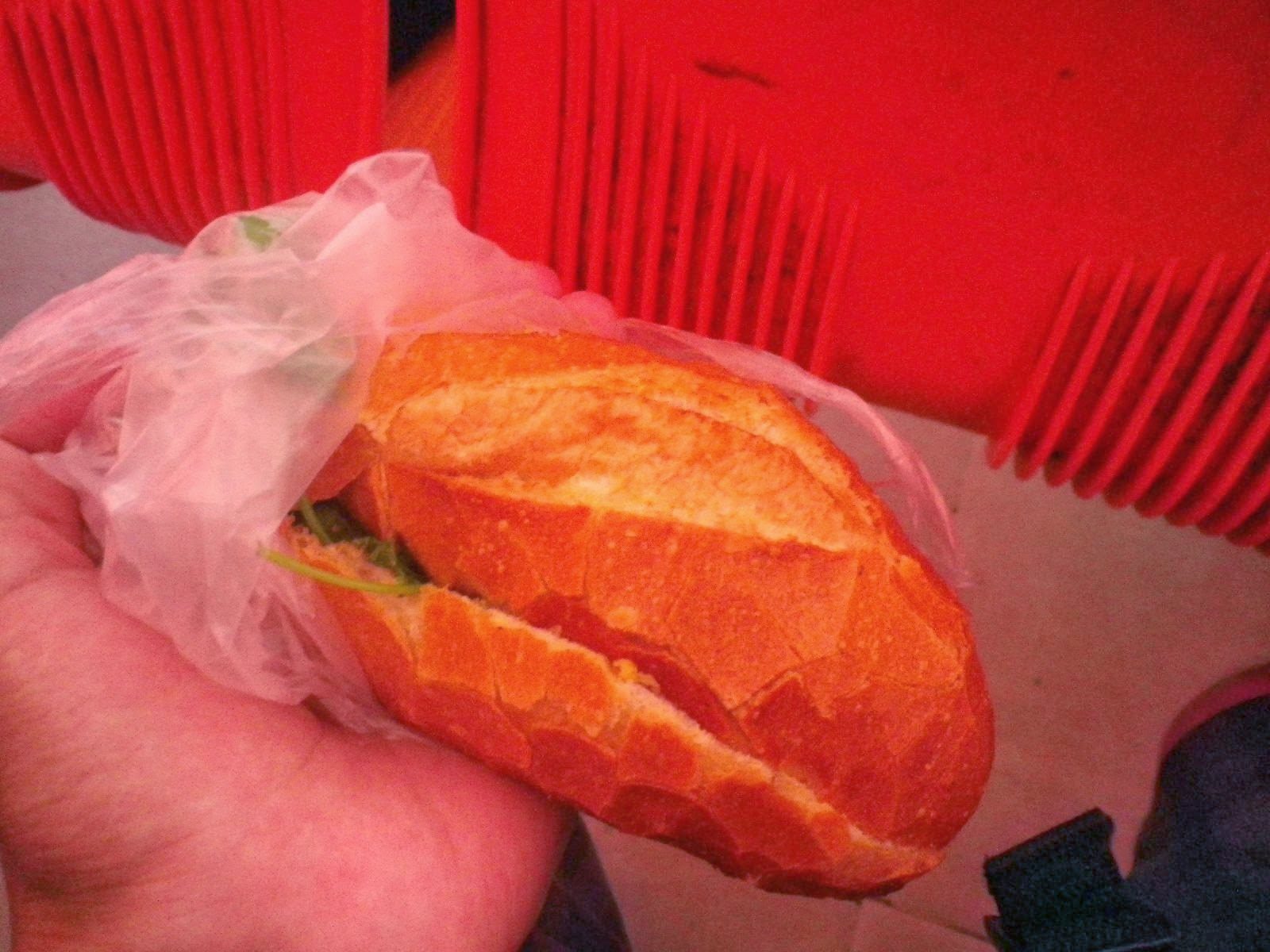 ビニール袋に包まれたバインミーを手に持つ