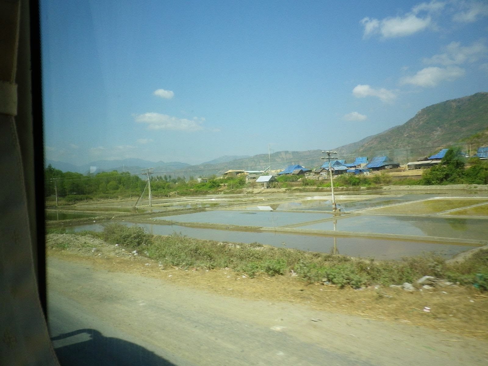 バスの車窓から見えるベトナムの塩田と山村風景