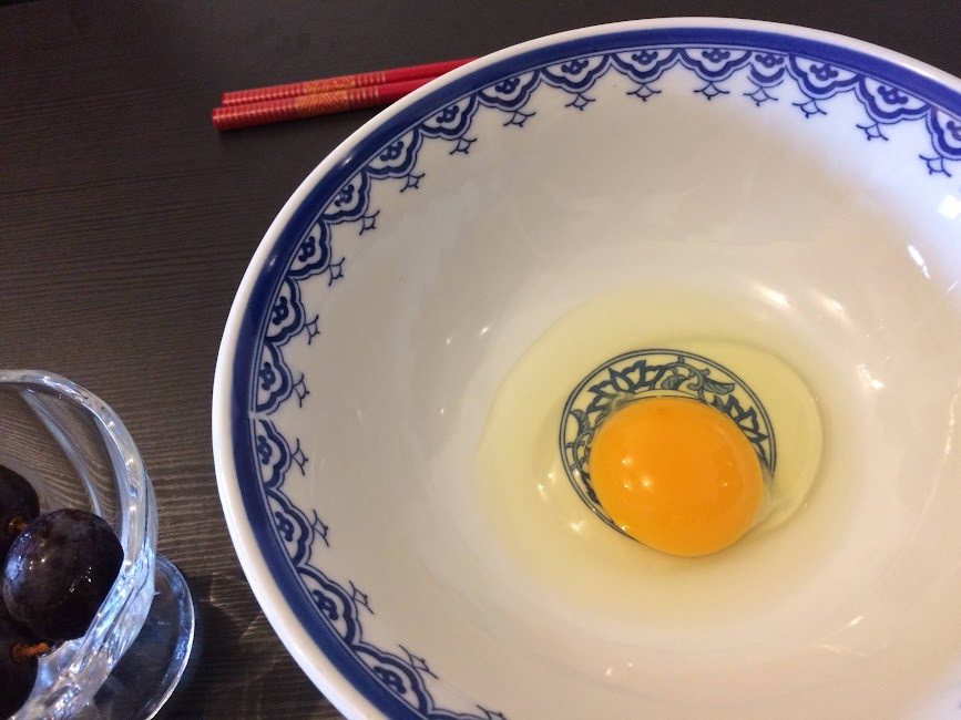 青絵柄の丼に割られた濃い黄身の生卵