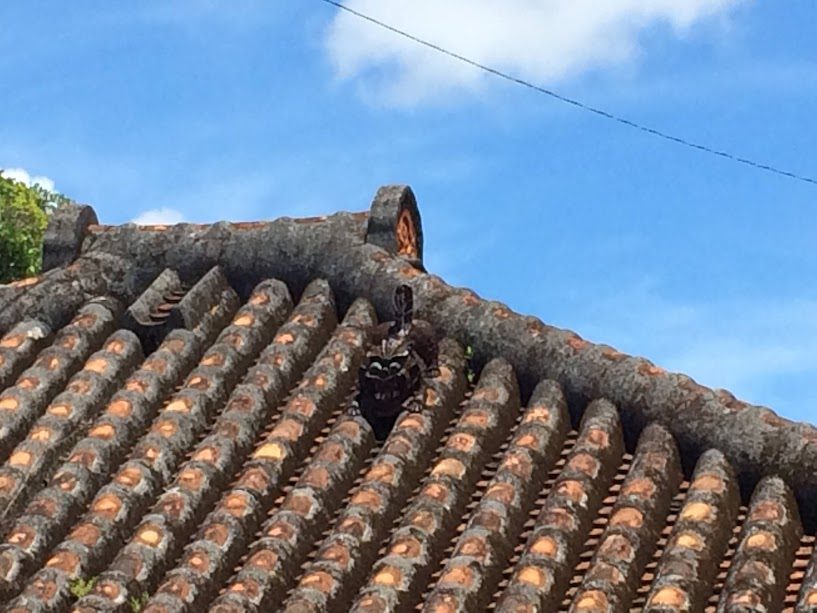 沖縄の赤瓦屋根に鎮座するシーサー像と青空