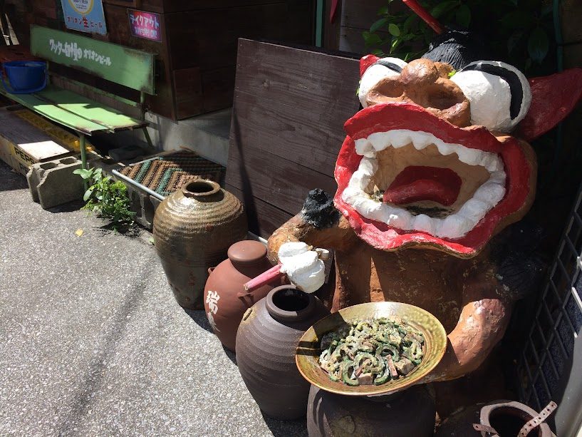 沖縄のシーサー像がゴーヤチャンプルを持つユニークなオブジェ