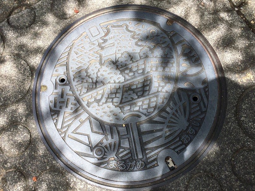 丸亀市のご当地マンホール蓋にデザインされた丸亀城とうちわ