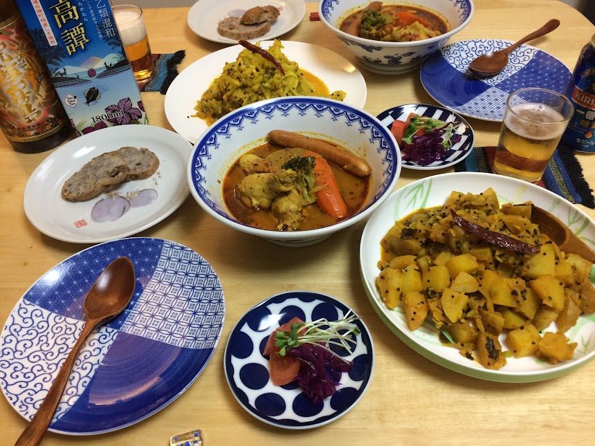 スープカレーとジャガイモ炒めなど多彩な自炊料理が並ぶ食卓