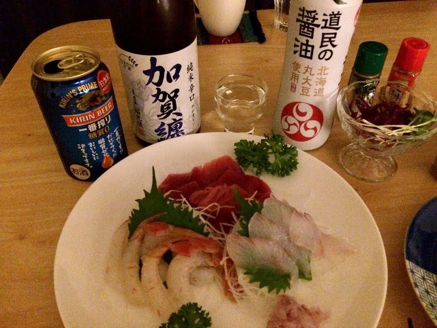 刺身盛り合わせと加賀鳶日本酒・道民の醤油が並ぶ食卓