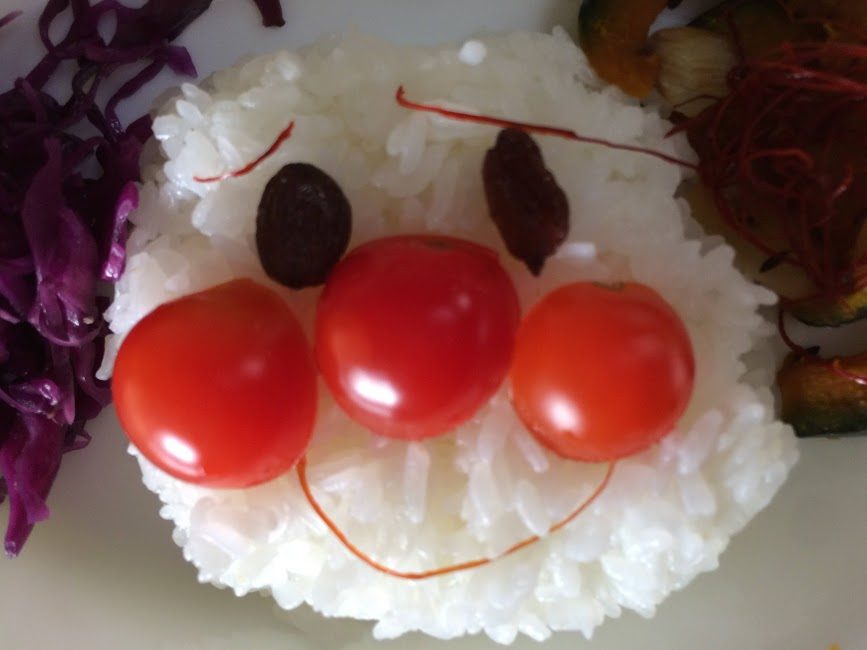 ご飯で作った笑顔のキャラクターにミニトマトをデコレーション